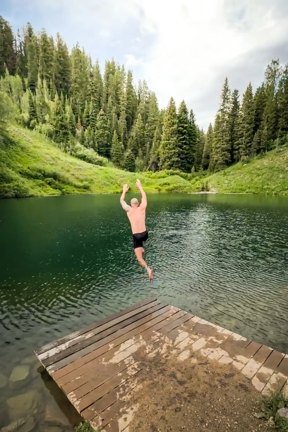 man jumping into a mountain lake
