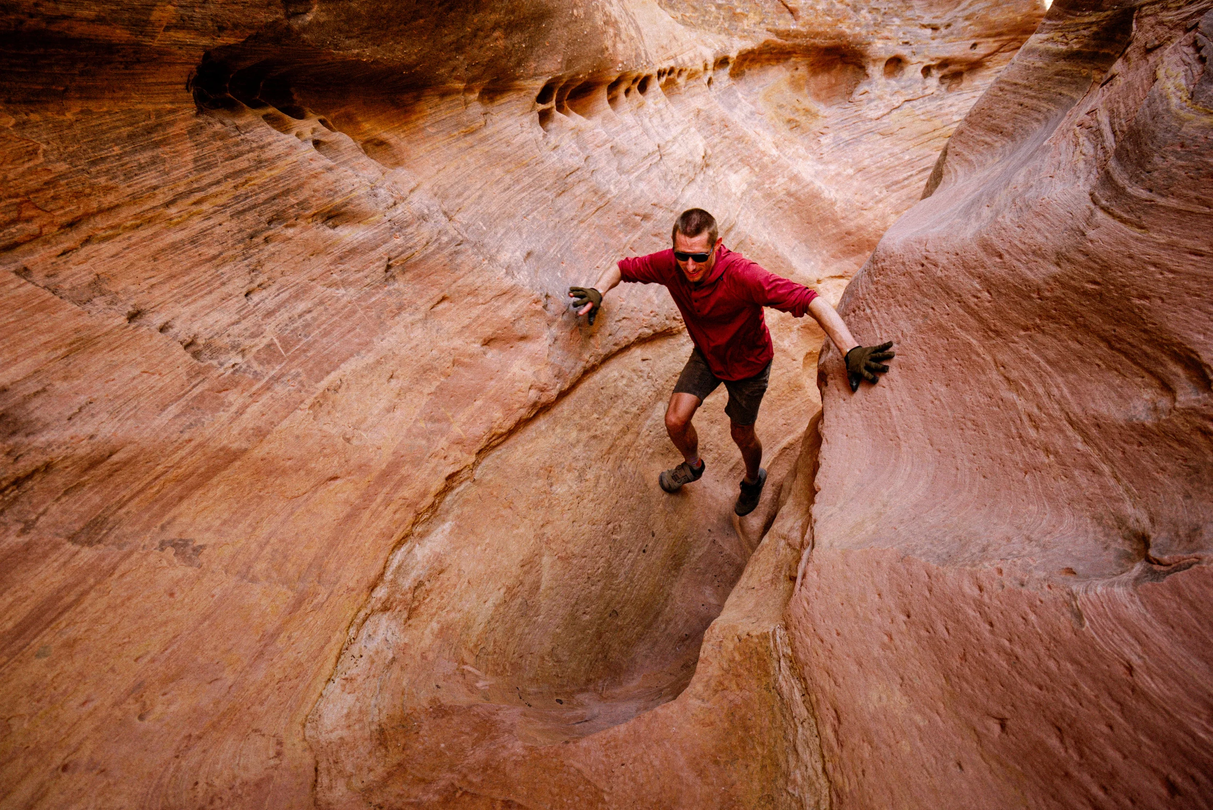 man in a red shirt hiking in a slot canyon