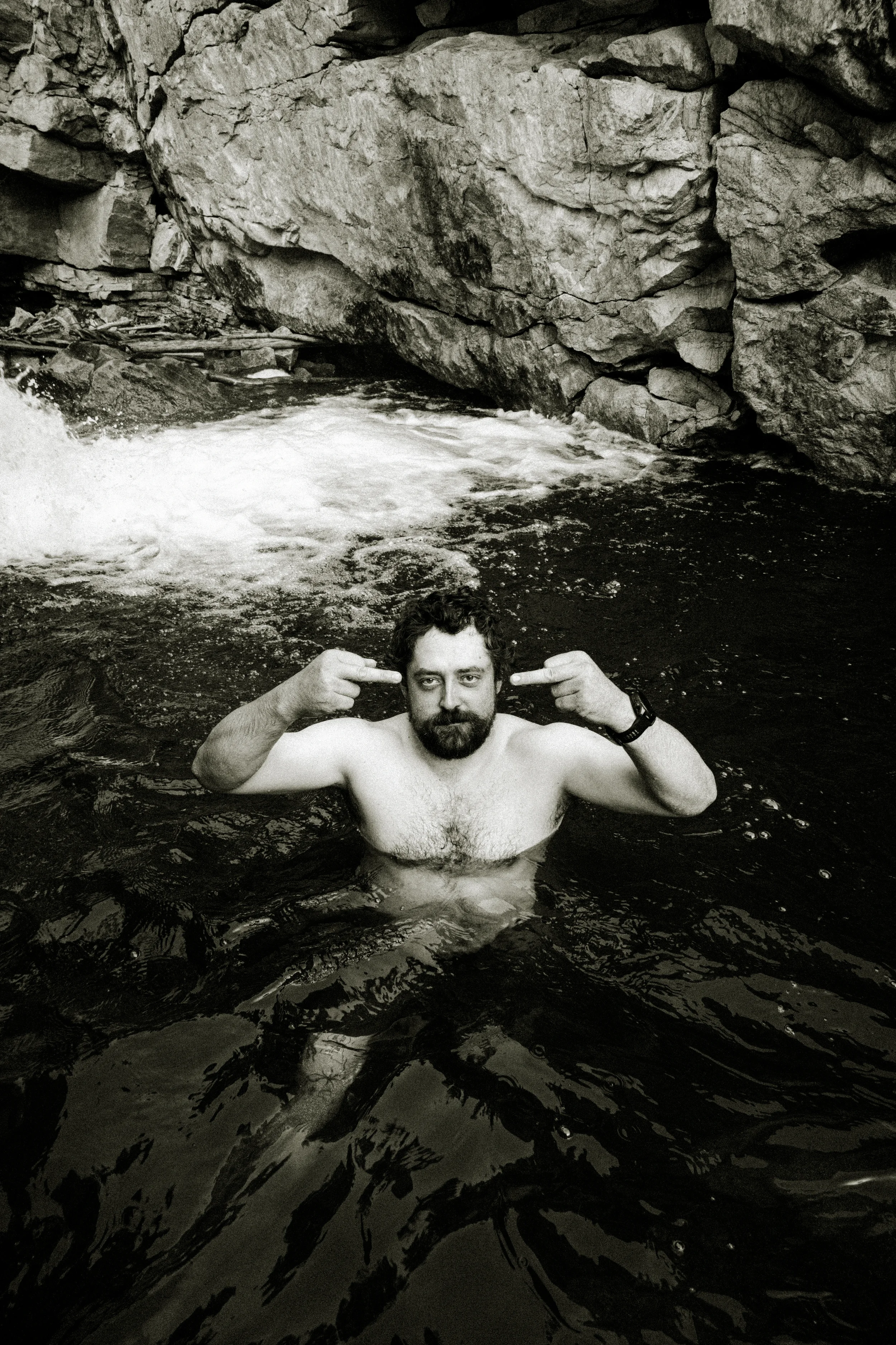 man flipping off a camera on a river