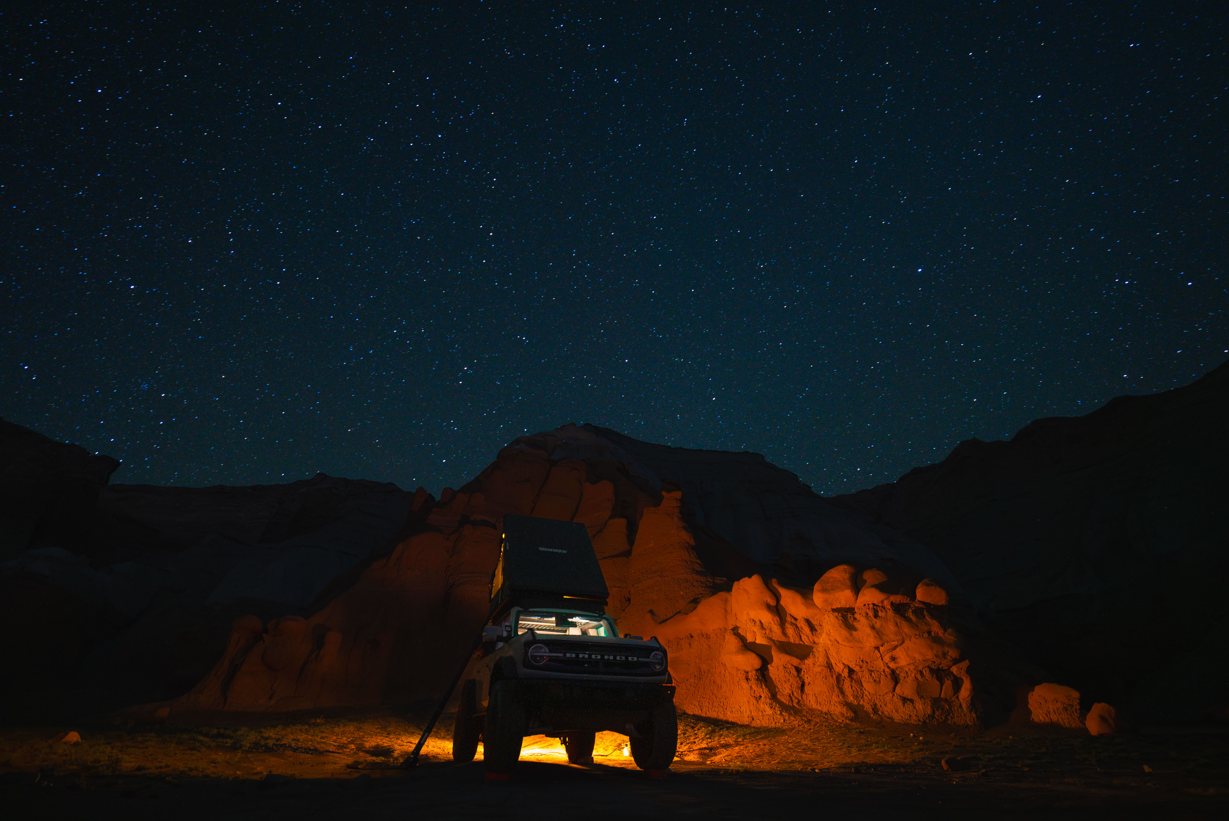 bronco in warm campfire glow with stars above