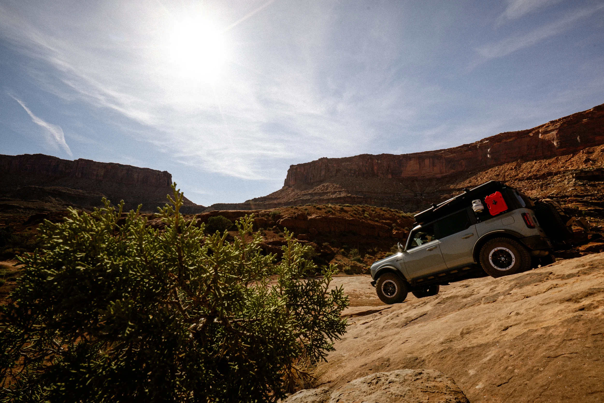 bronco driving down a steep sandstone slab