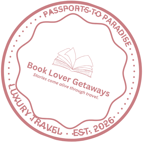 A pink and black circular logo for Book Lover Getaways featuring an open book and the slogan "Stories come alive through travel,” surrounded by the text "Passports to Paradise, Luxury Travel, Est. 2026."