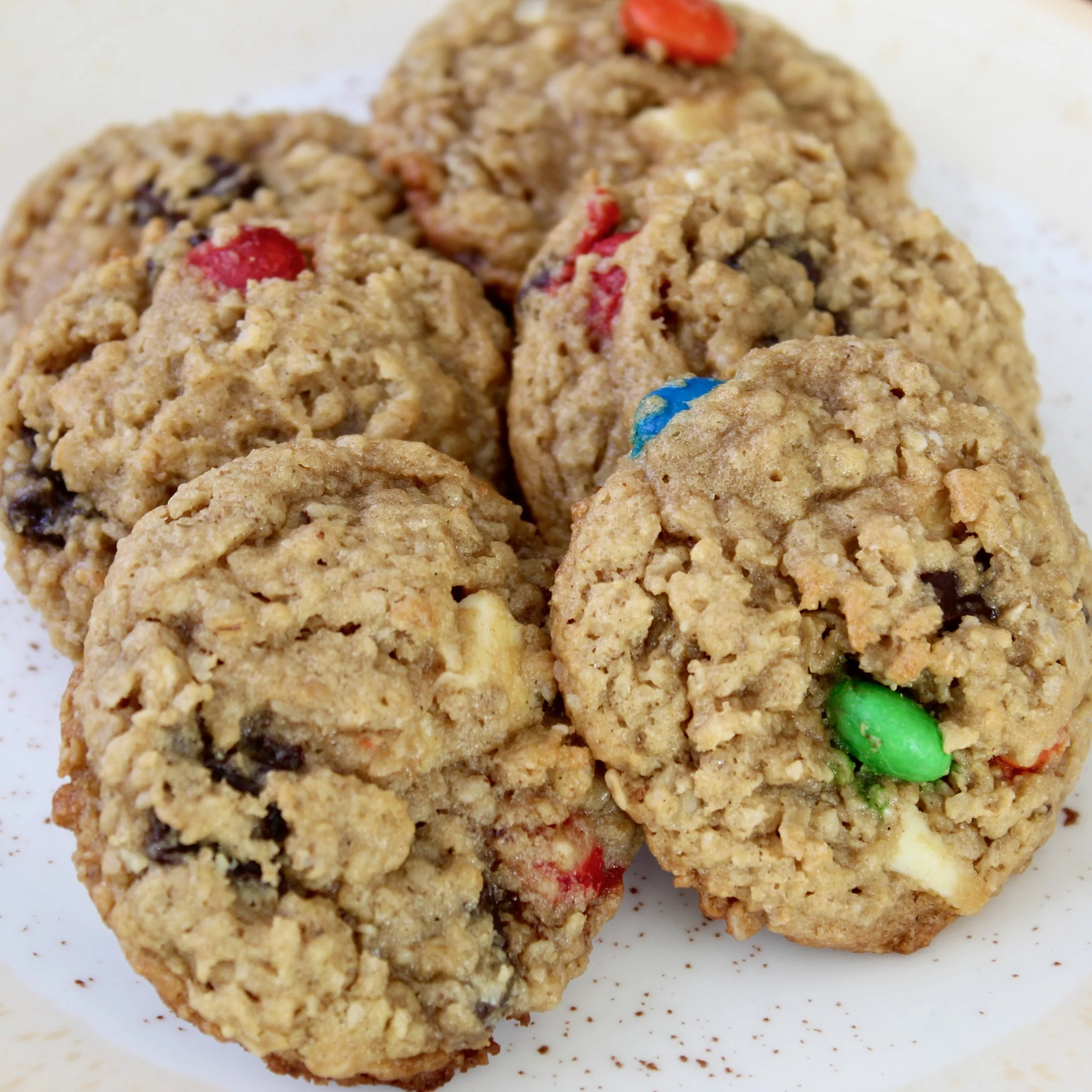 Close-up of a pile of soft oatmeal monster cookies studded with colorful M&M candies and chocolate chips.