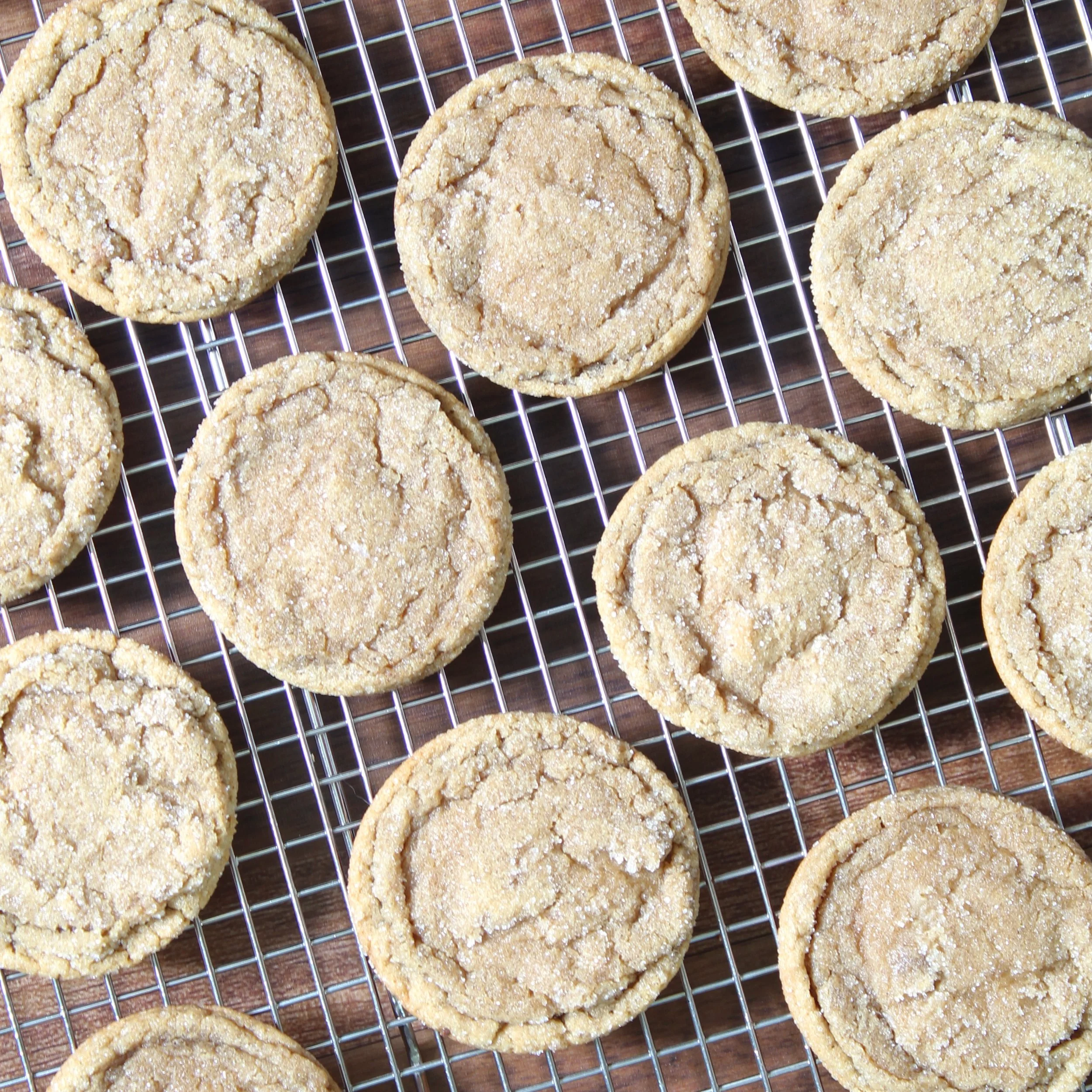 Flat-lay overhead view of freshly baked brown butter espresso cookies cooling on a wire rack over a wooden surface.