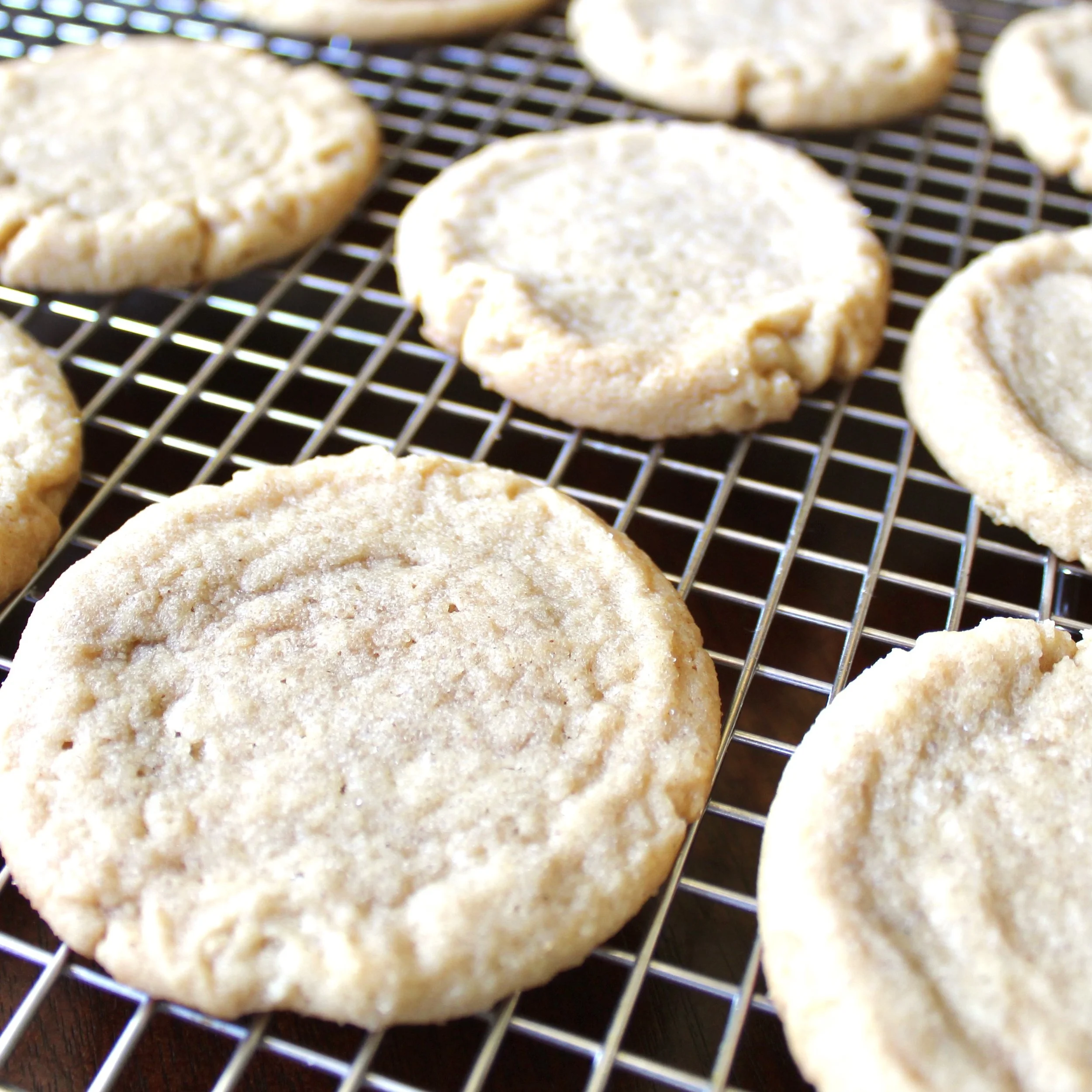 Freshly baked peanut butter cookies cooling on a silver wire kitchen rack.