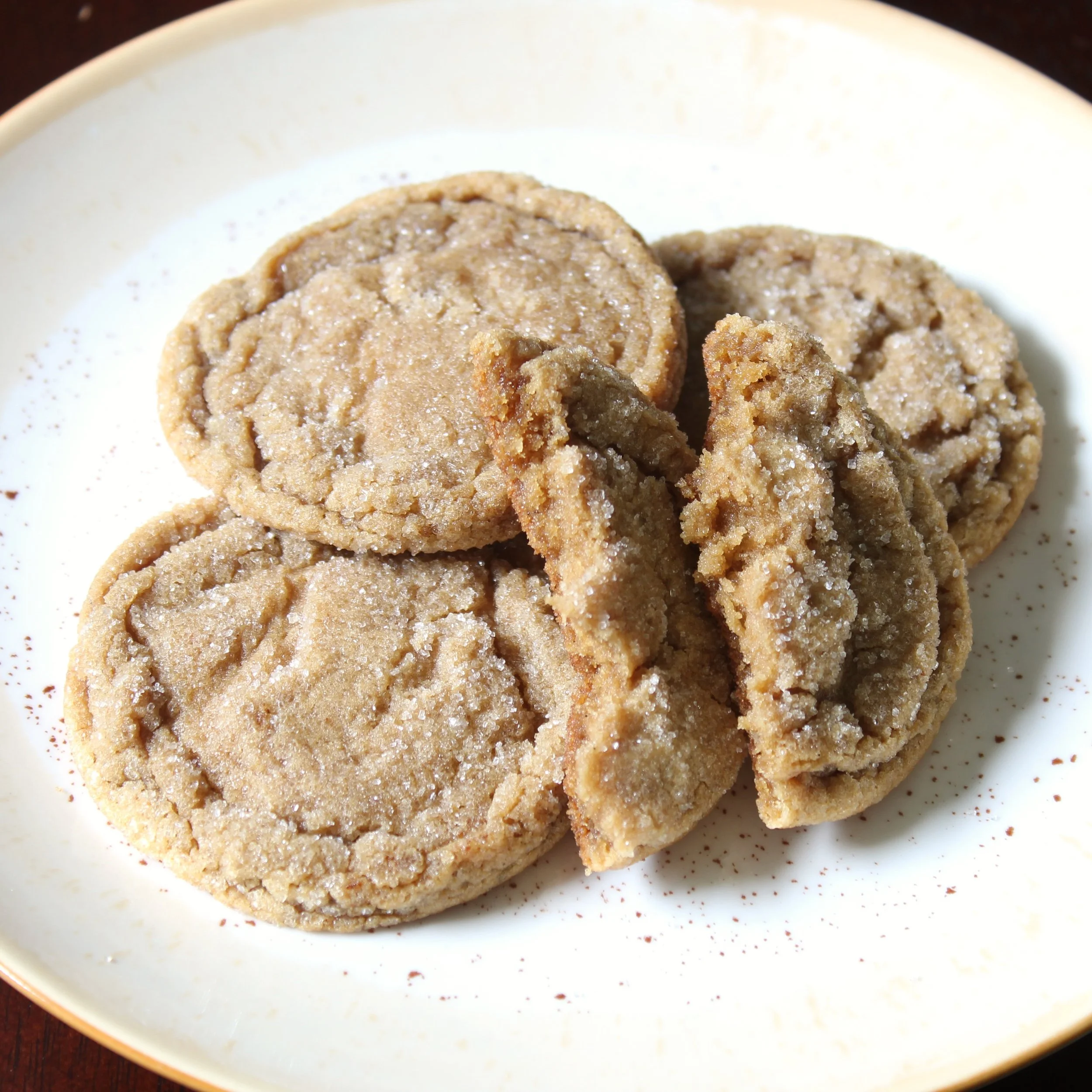 Chewy brown butter espresso cookies on a plate with one broken open, showing soft texture and fine sugar dusting.