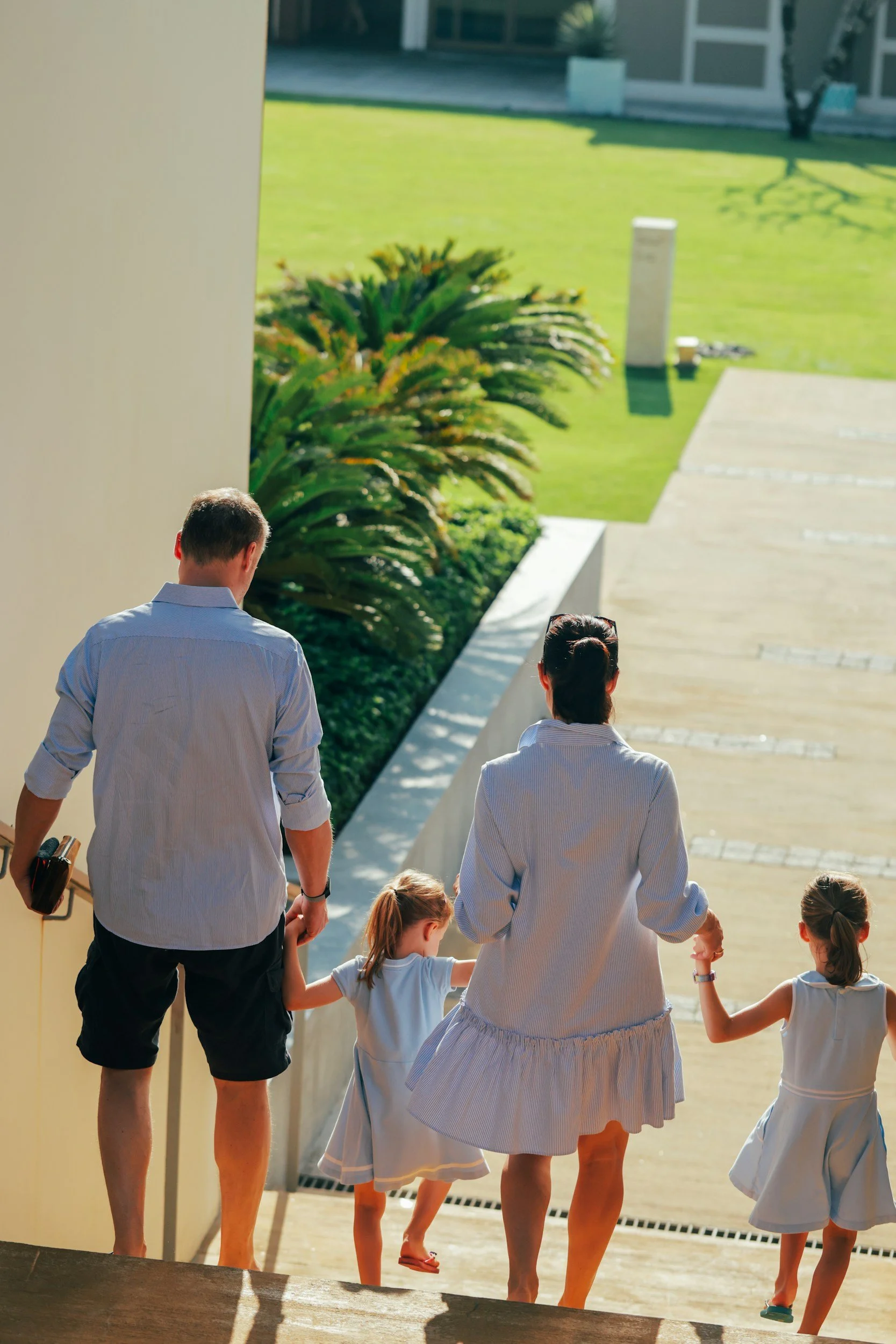 A couple and their 2 kids holding hands walking down the stairs