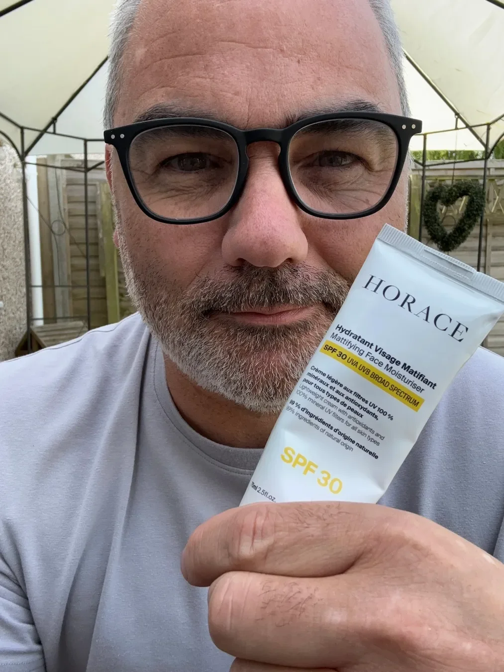 Jerome holding a tube of Horace Mattifying Face Moisturiser SPF 30, explaining the importance of sun protection when using Vitamin C and Peptide serums.