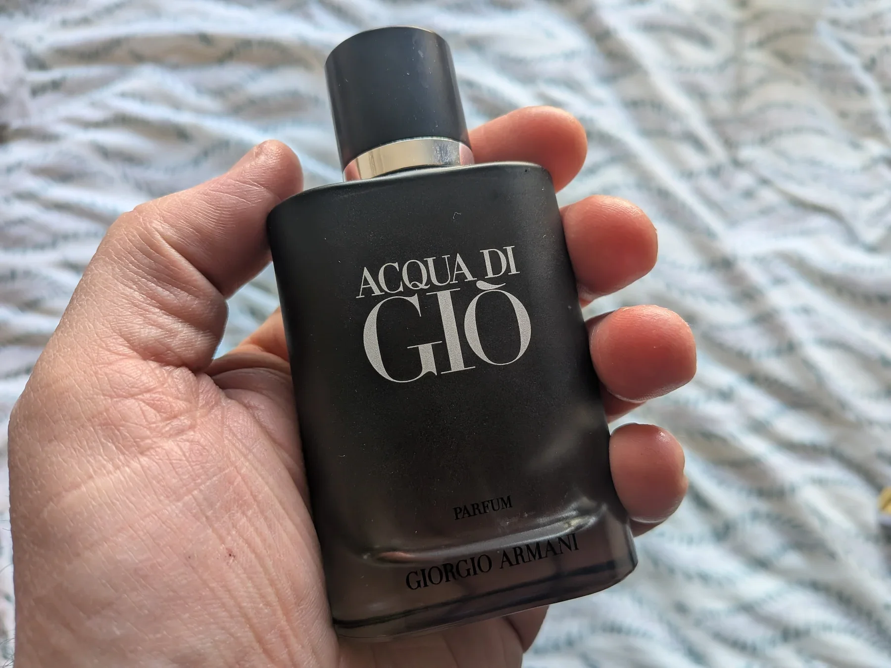 Jerome holding a bottle of Giorgio Armani Acqua di Giò Parfum to demonstrate the difference in fragrance concentrations for mature men.