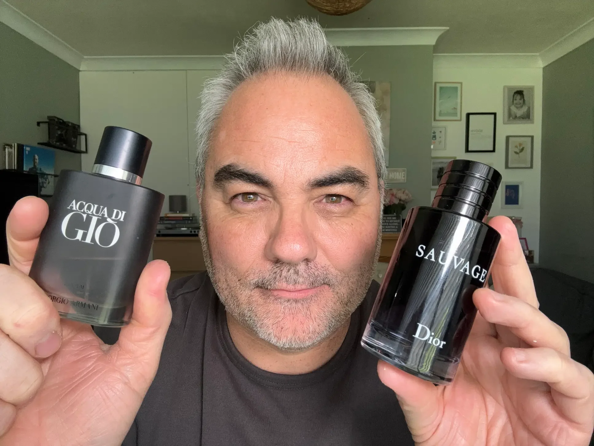 Jerome from By Jerome holding up bottles of Acqua Di Giò and Sauvage Dior fragrances while presenting a curated guide for men over 50.