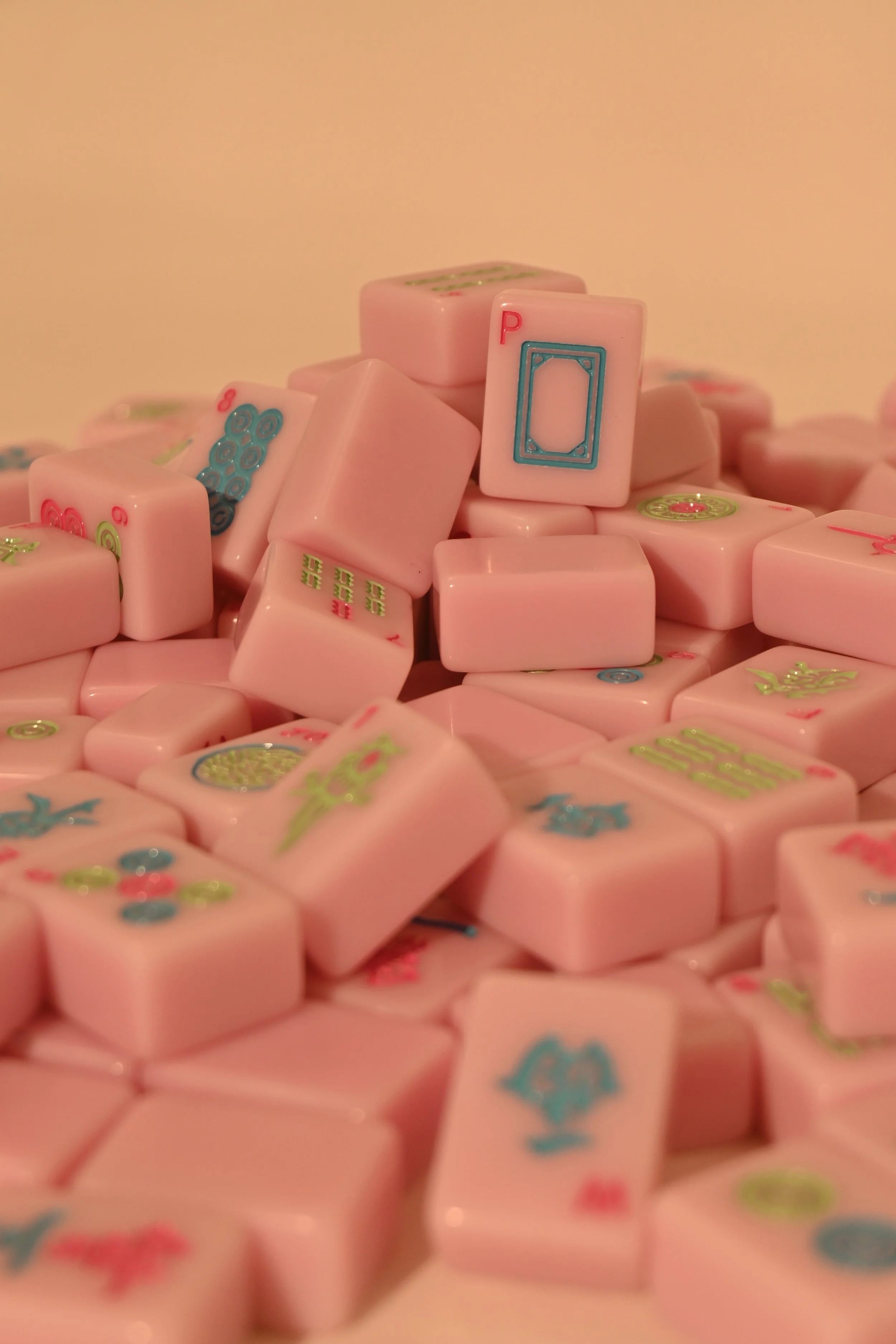 Pile of pink Mahjong tiles with various colorful designs and characters on them.