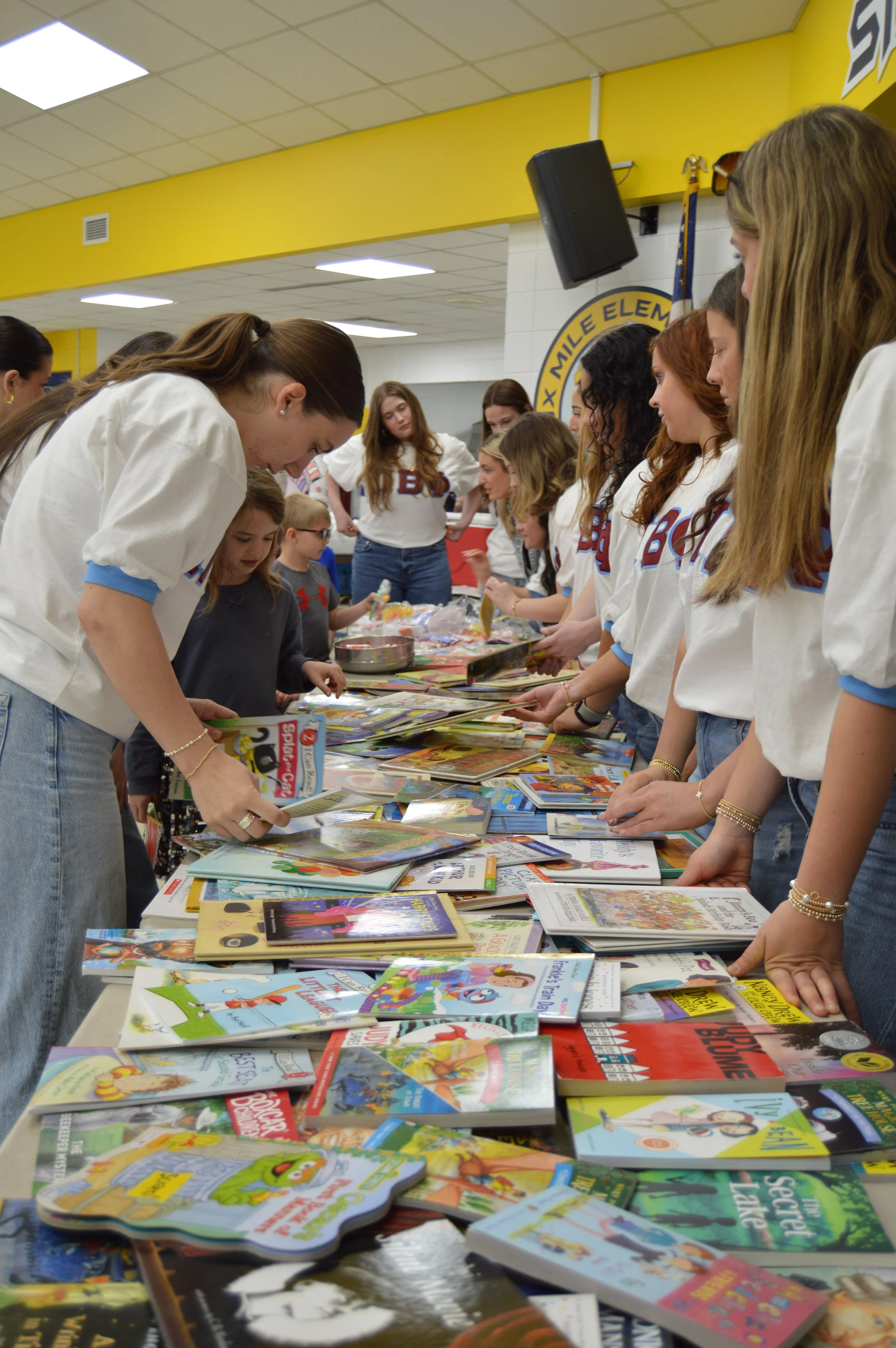 Group of students at a book fair browsing through colorful books on a table.