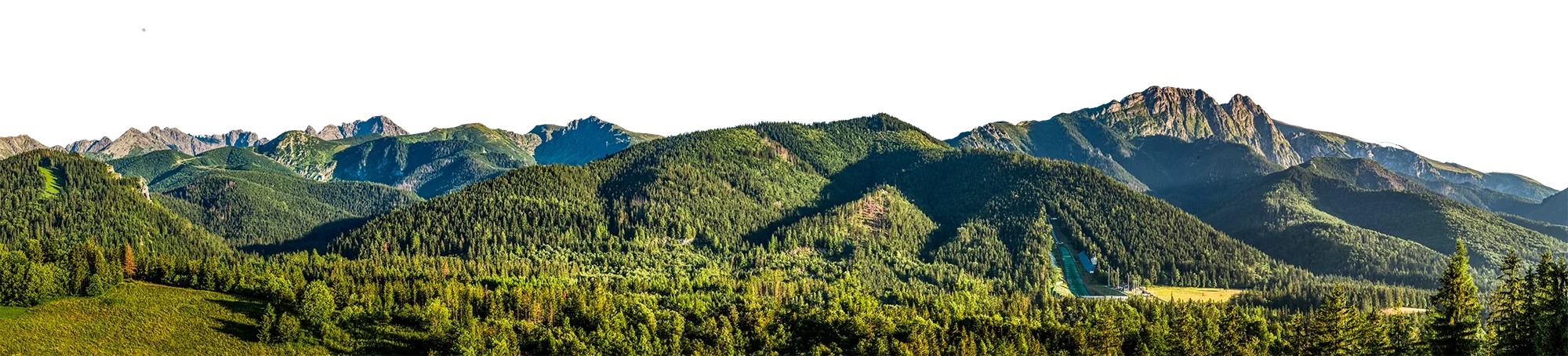 Mountain landscape with lush green forests, mountain peaks, and clear blue sky.