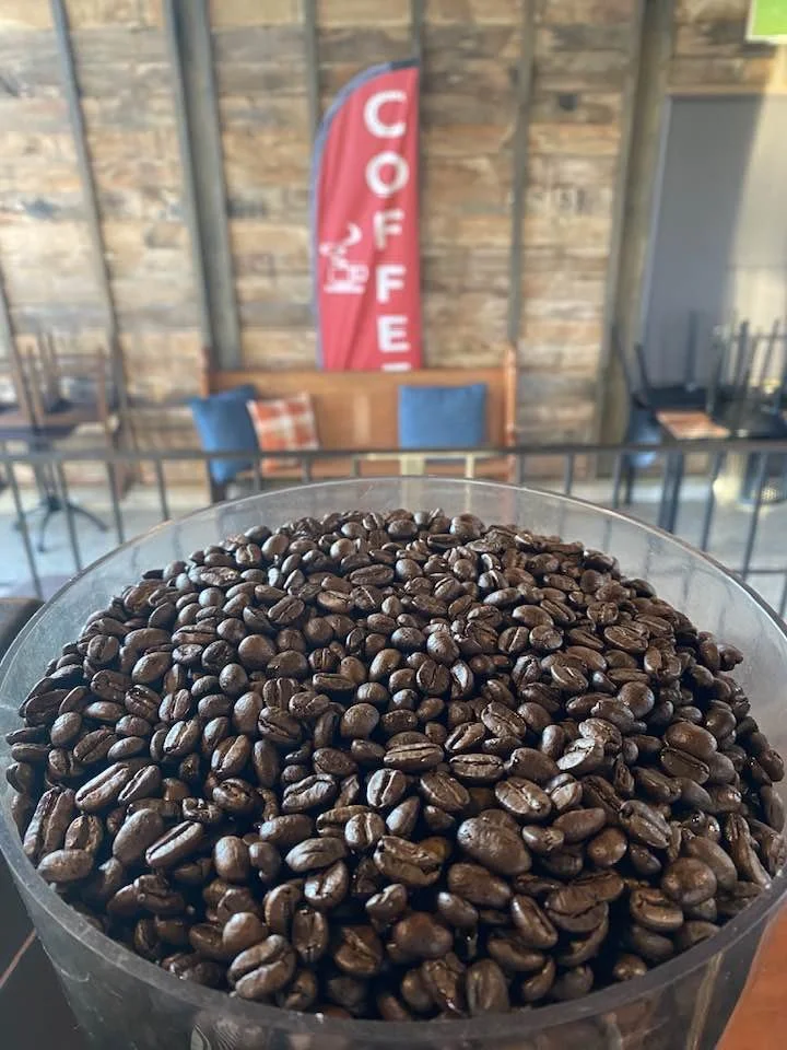 Close-up of a container filled with roasted coffee beans in a coffee shop setting.