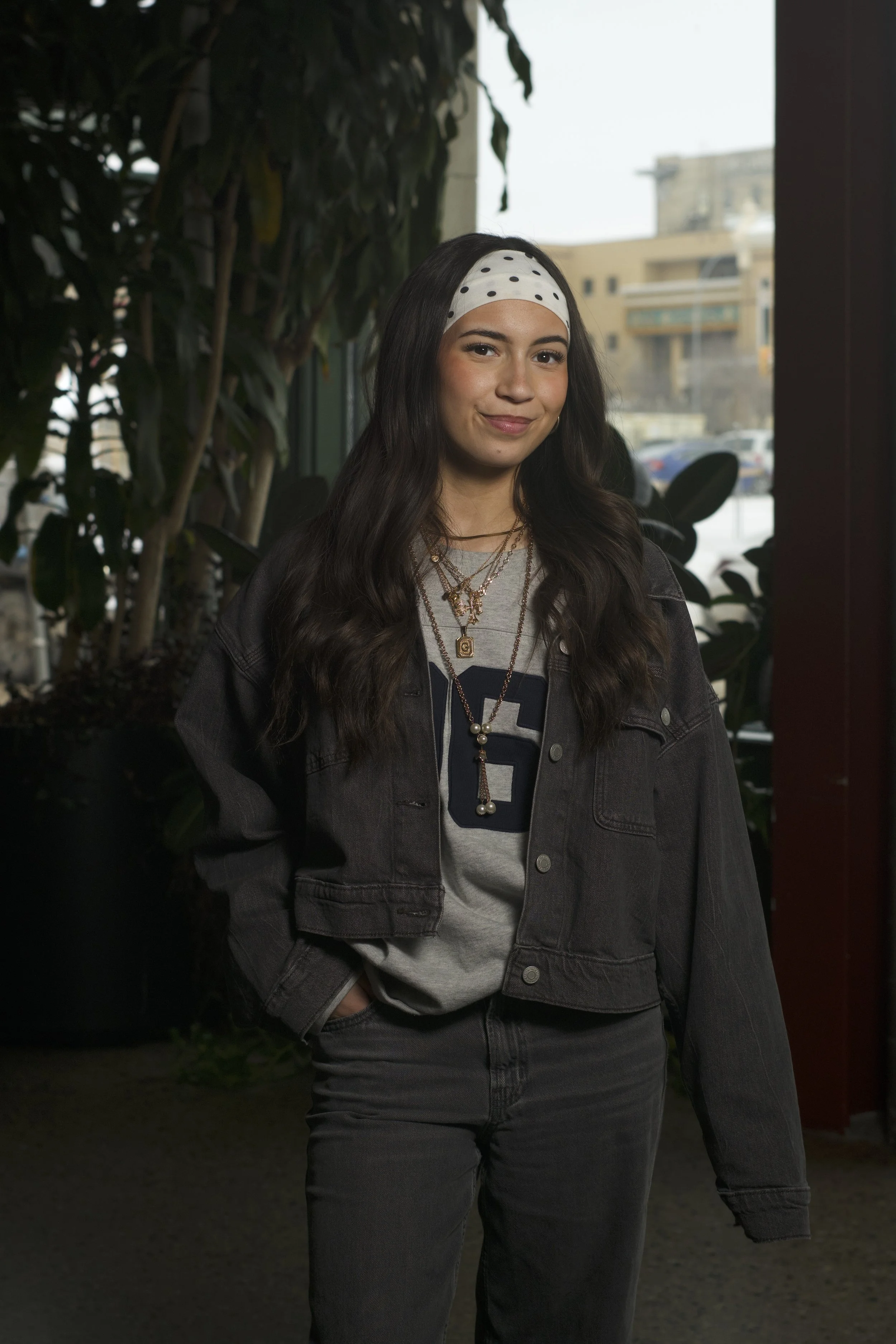 Woman standing and smiling at camera with one hand in pocket