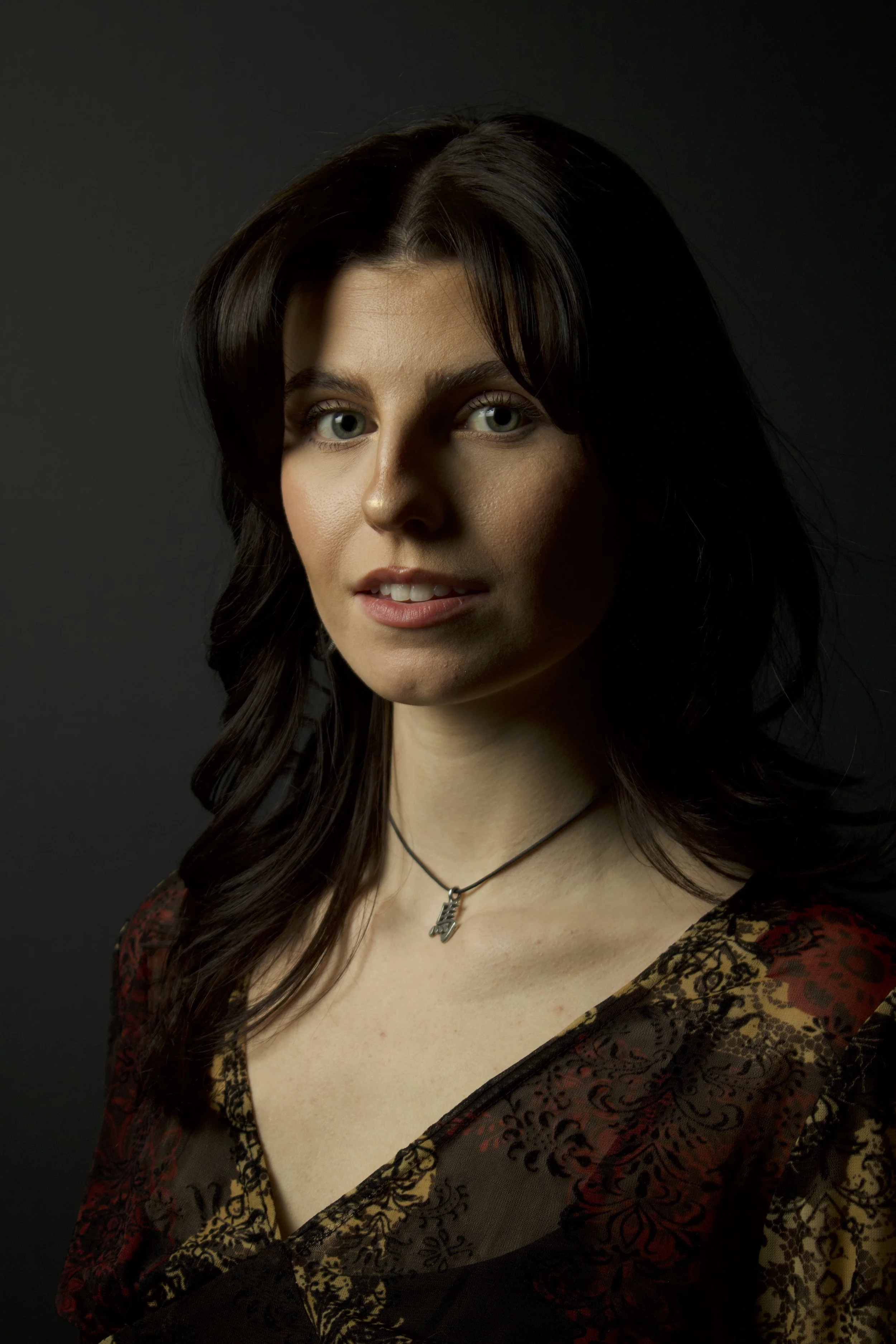 portrait of woman posing next to a black wall