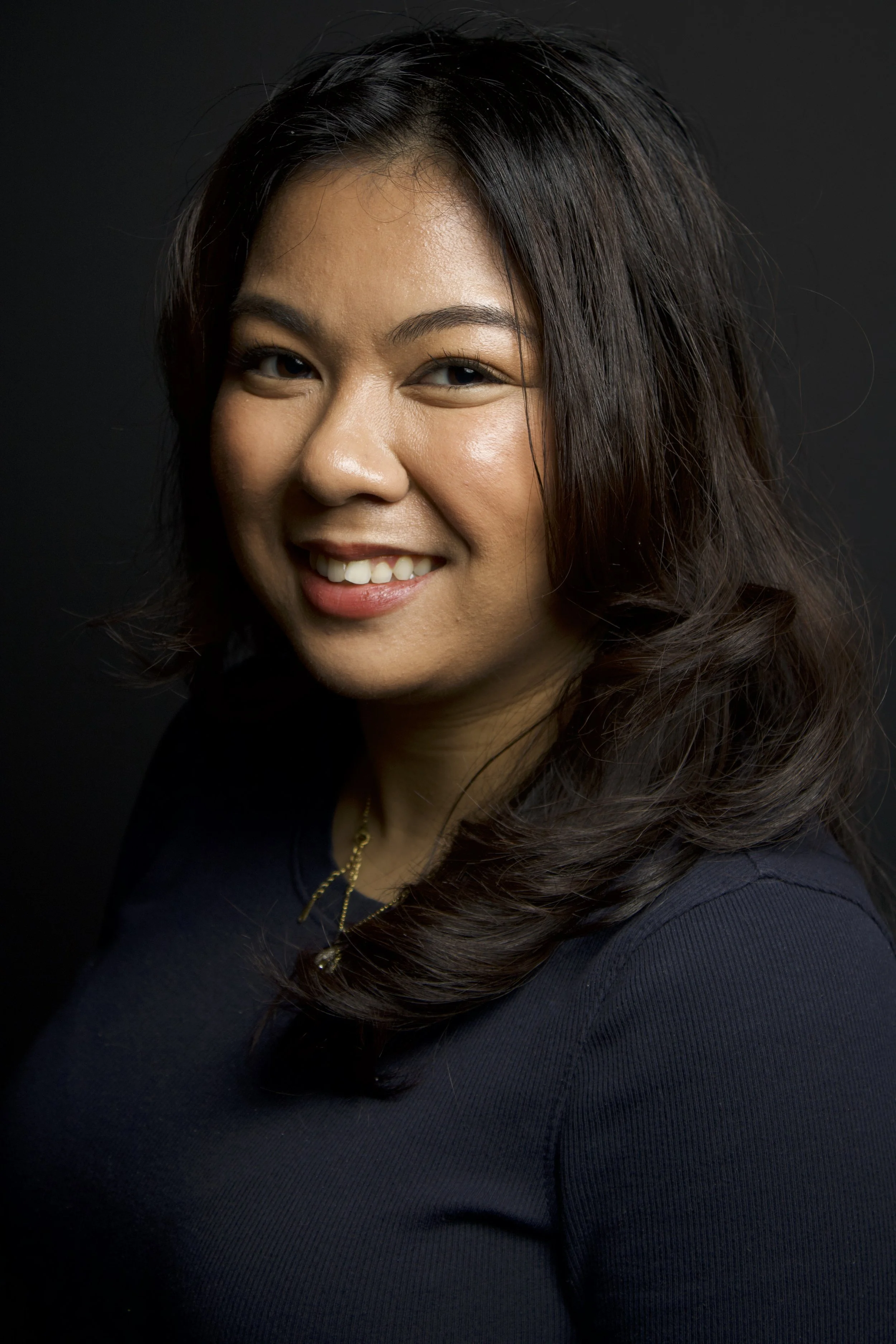 close up of woman smiling against black wall