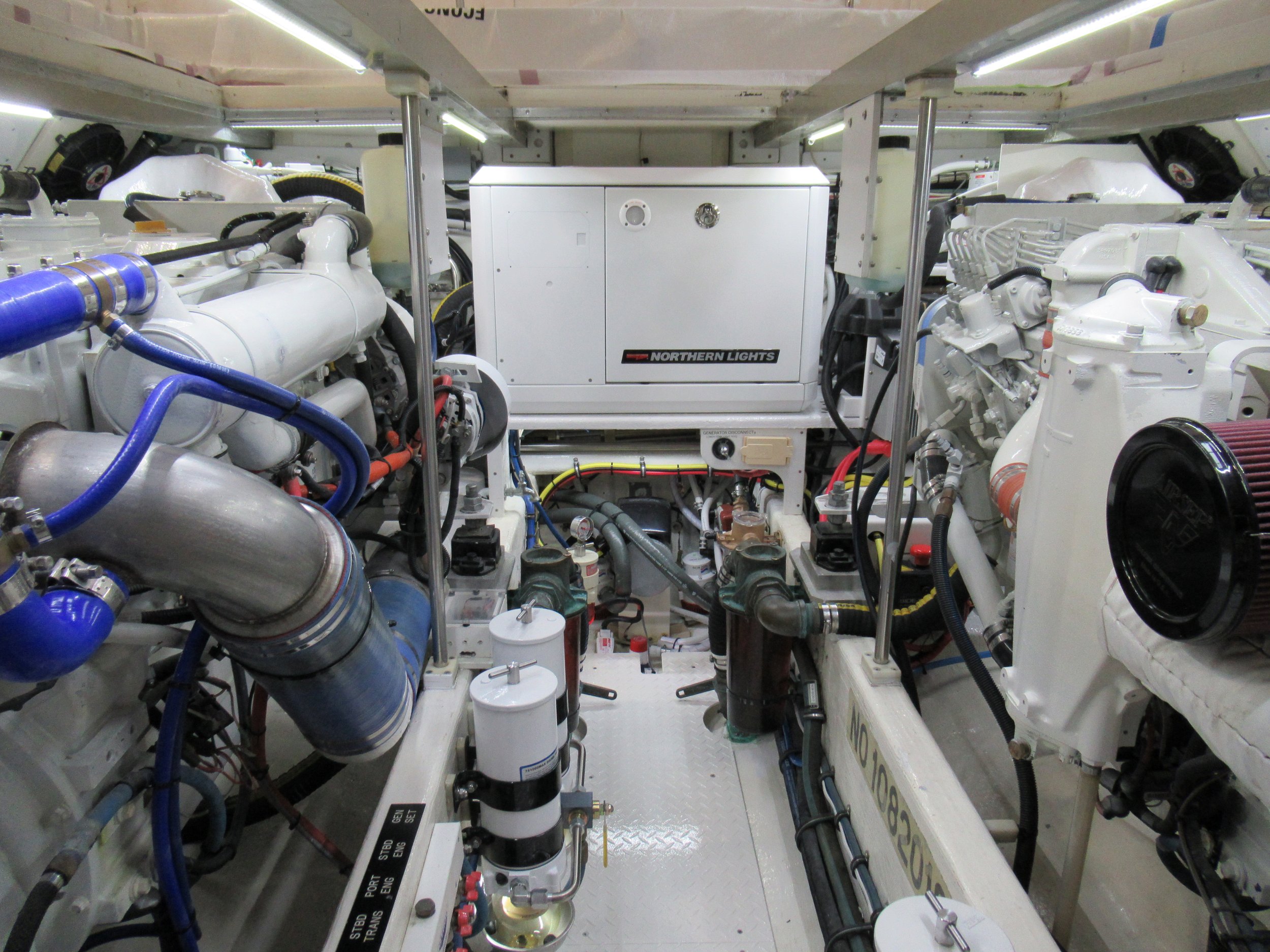 Interior view of a machinery room with white mechanical equipment, pipes, and wiring, including a white box labeled 'Northern Lights' in the center.