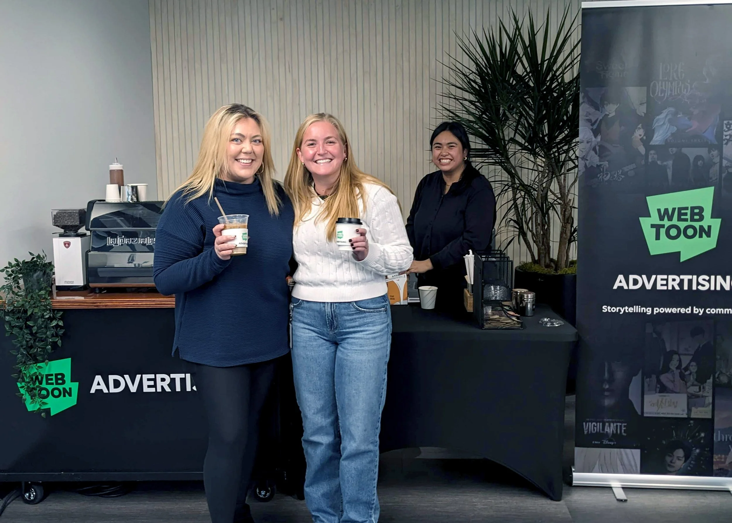 Two women in front of the coffee cart smiling with their coffee beverages in hand