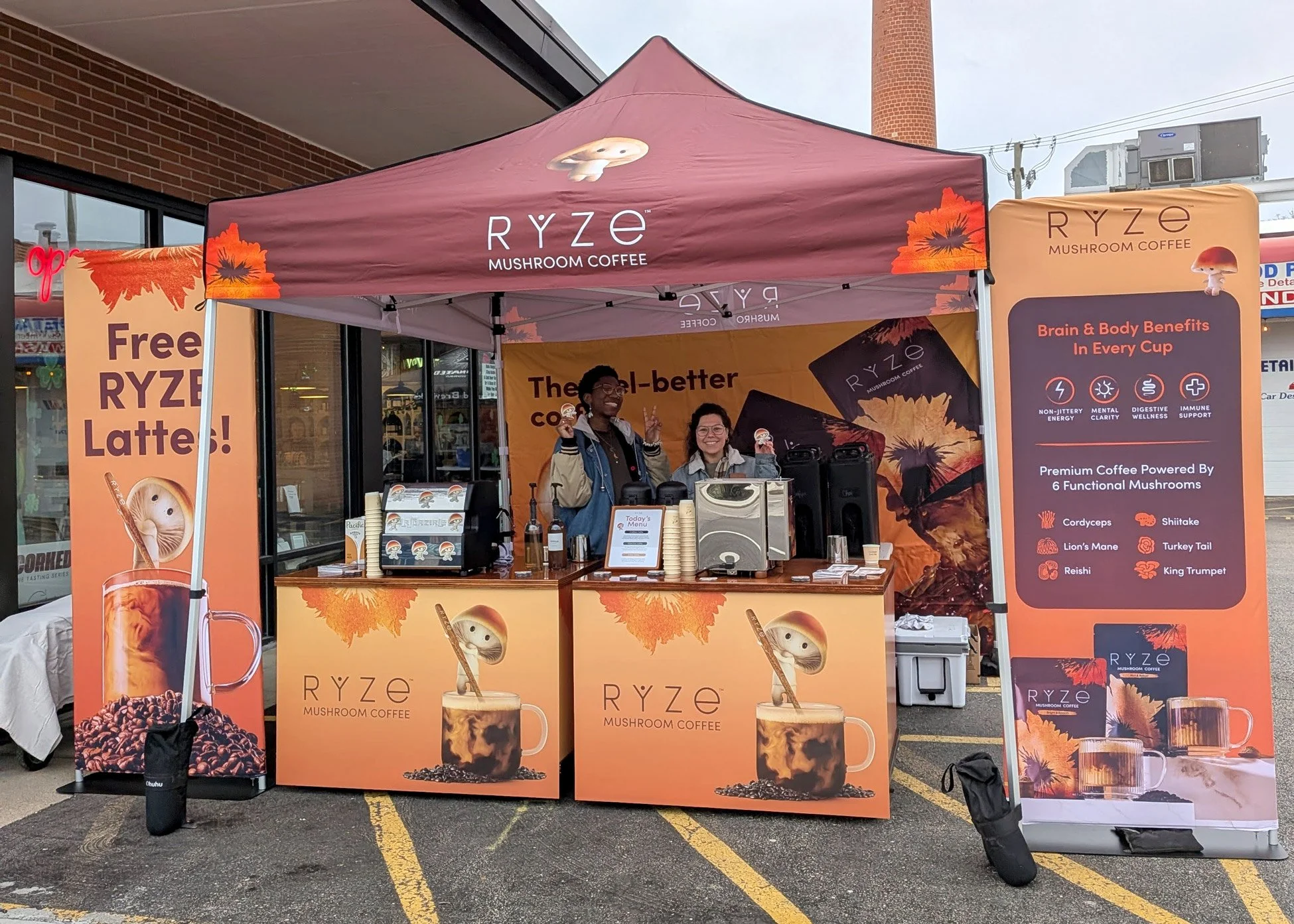Two baristas behind a branded cart and booth for Ryze coffee