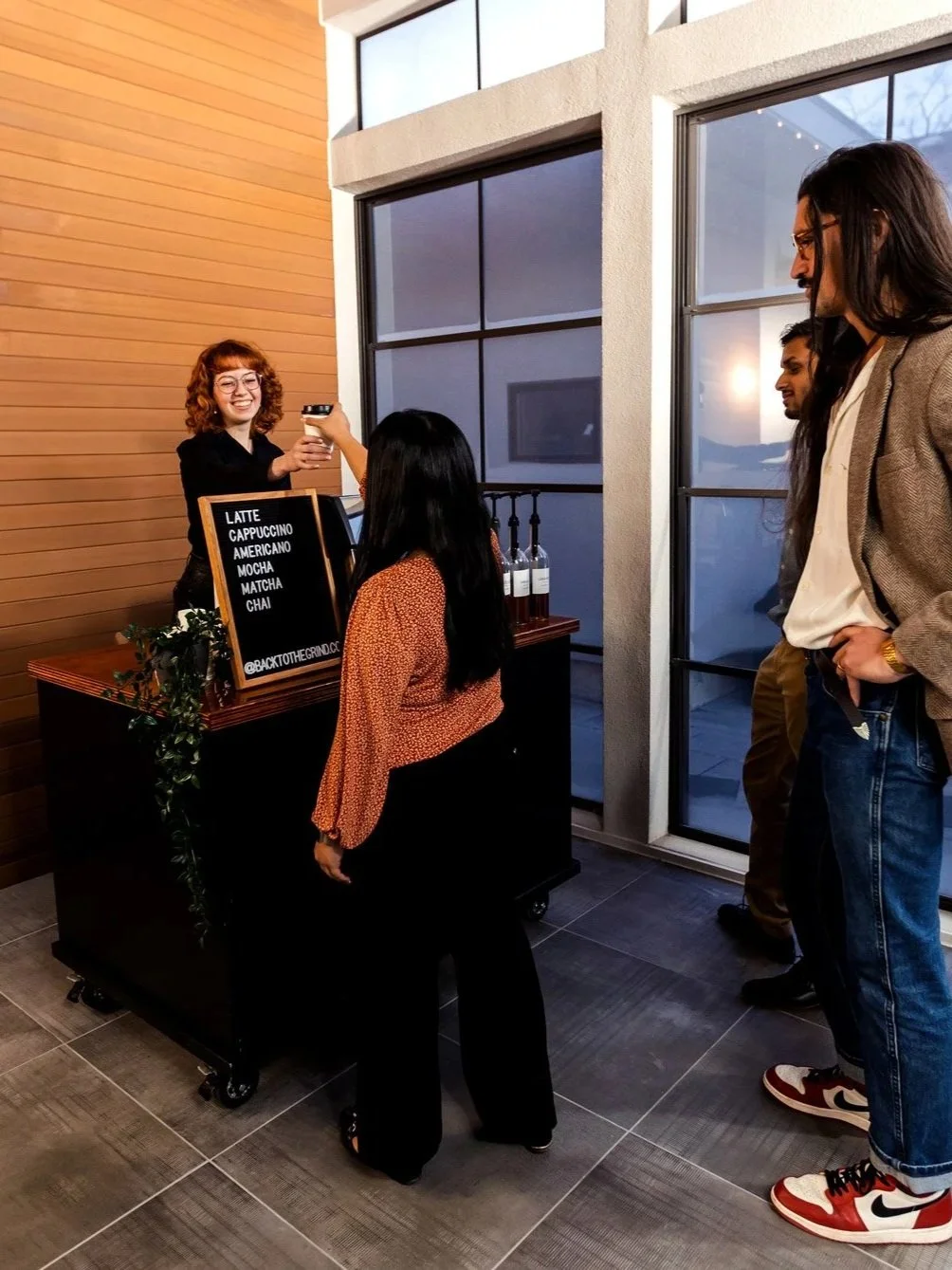A barista behind the coffee cart handing a cup to a customer