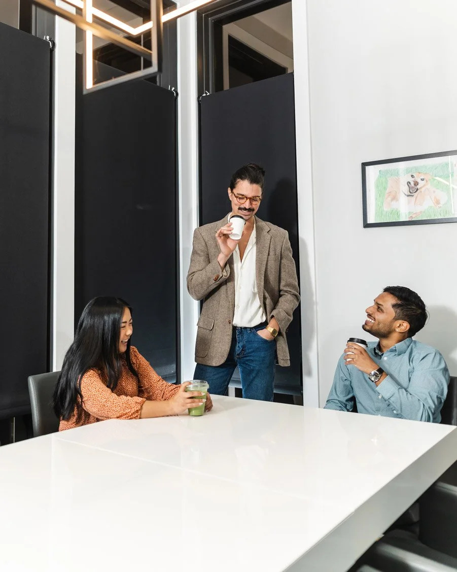 Three people in a conference room enjoying their beverages from the coffee cart