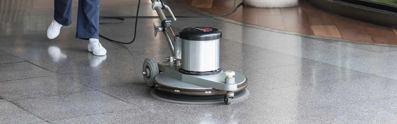 Floor cleaning machine in use on a shiny, polished floor.