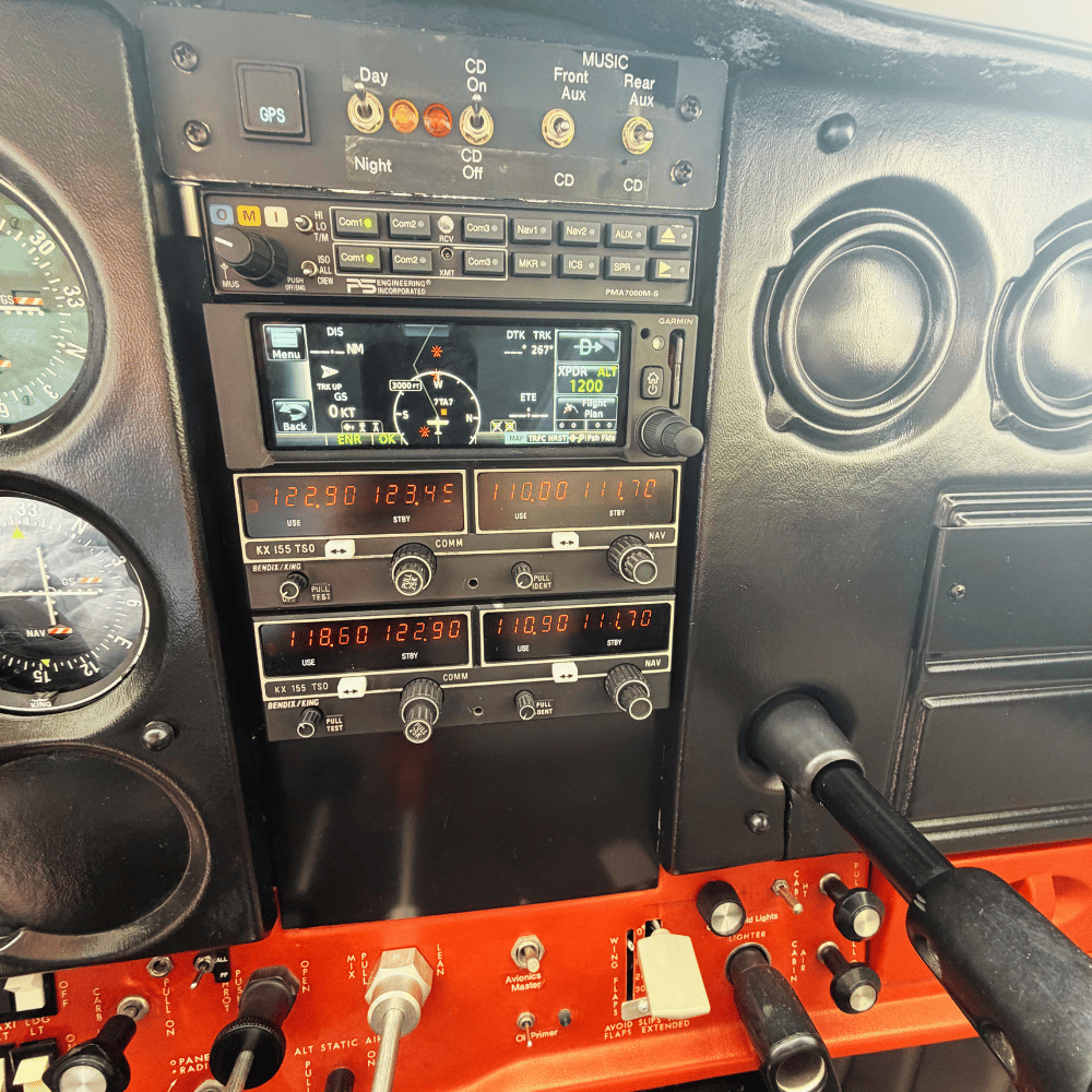 The cockpit dashboard of a small airplane featuring navigation and communication instruments, engine monitors, and various switches and controls.