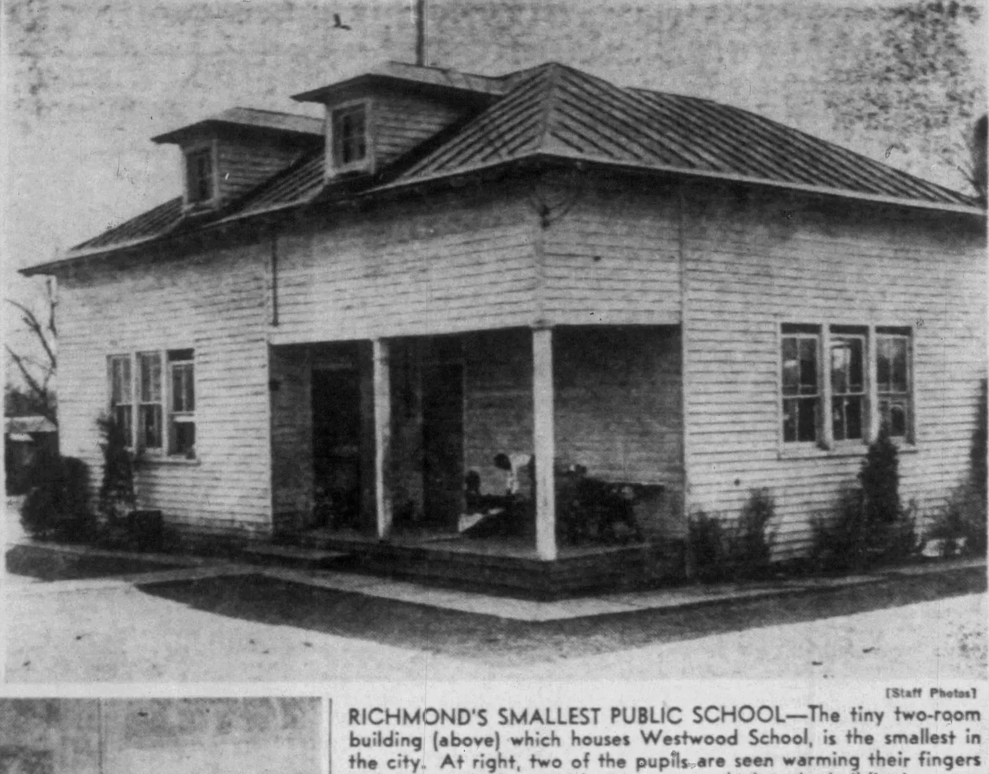 Old black and white photo of a small, two-story wooden house with a gabled roof and three dormer windows. The house appears to be under construction or renovation, with an open front entrance and visible structural supports.