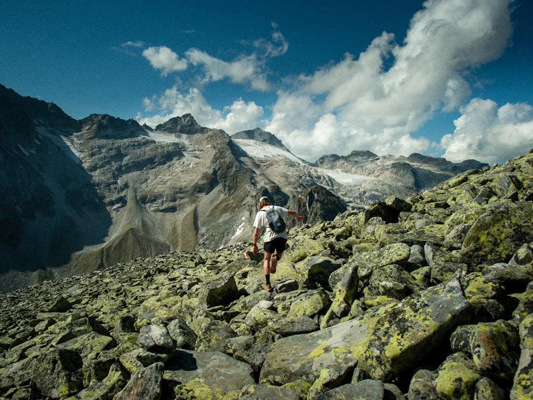 A person hiking on a rocky terrain in a mountainous landscape during the day.