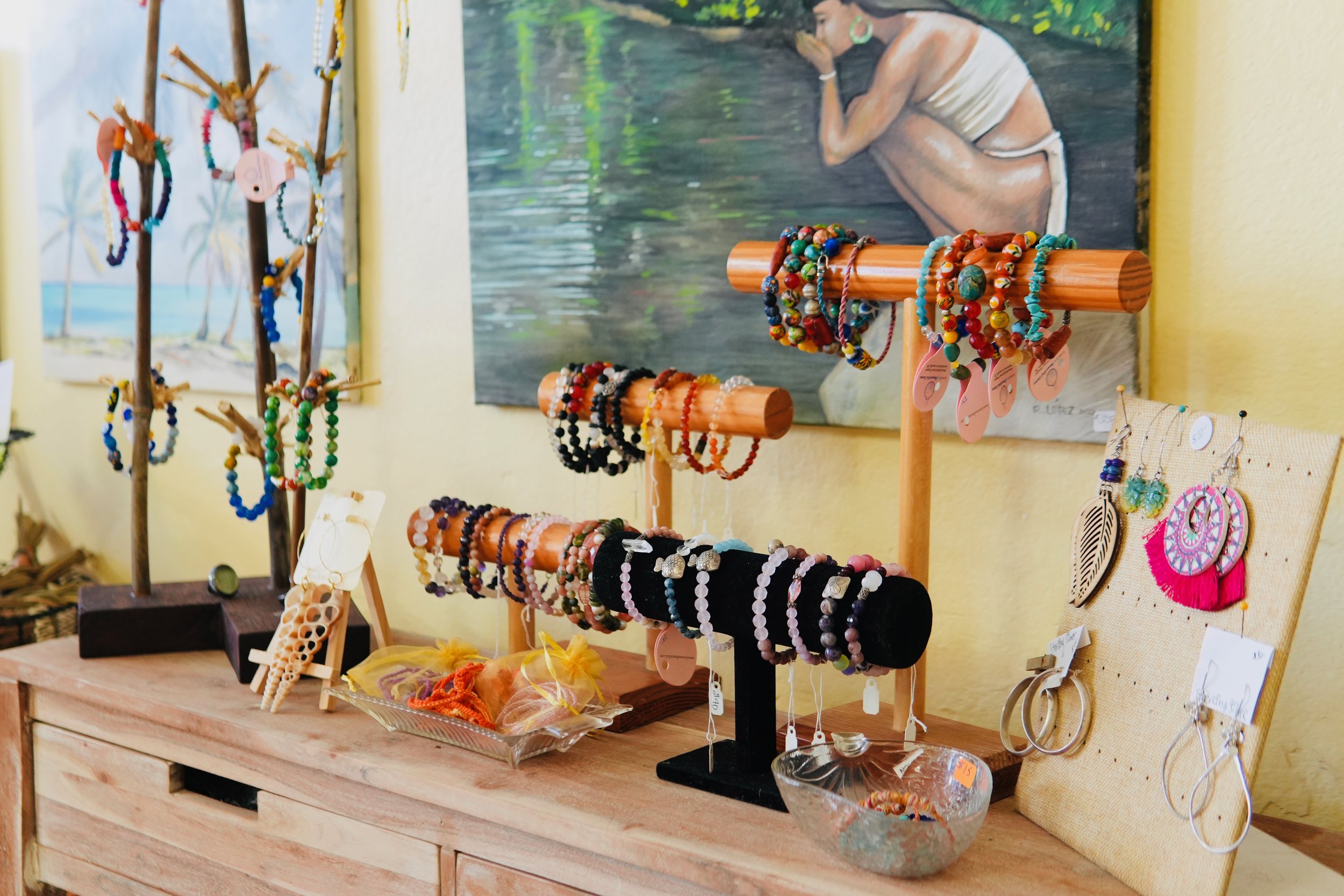 Display of colorful handmade jewelry, including bracelets and earrings, arranged on black and wooden stands at a craft fair or boutique.