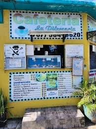 Yellow outdoor kiosk with a sign that says 'Cafeteria La Conquista' with menu boards and potted plants.