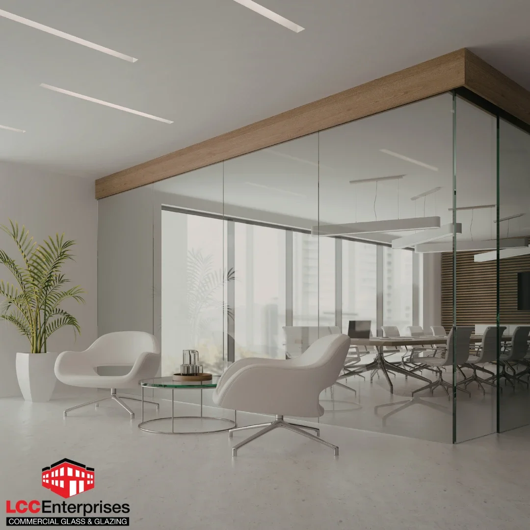 modern commercial office interior in Harrisonburg, Virginia featuring frameless glass partition walls with a wood-trimmed ceiling header, white lounge chairs in the foreground