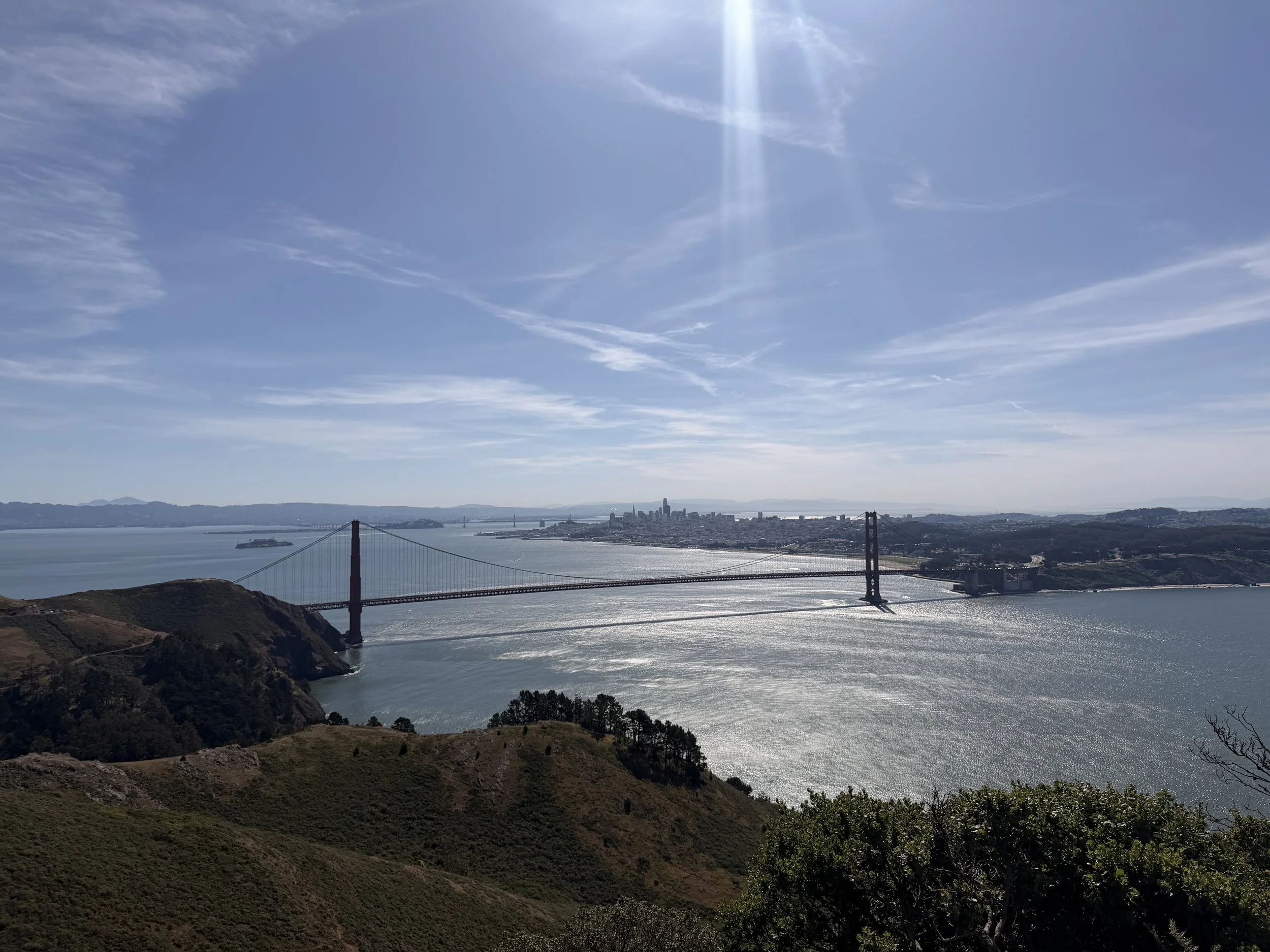 A view of the Golden Gate Bridge in San Francisco beneath a bright, sunny sky with scattered clouds.