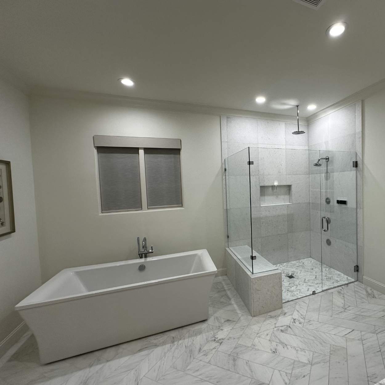 Modern bathroom with a white bathtub, a glass-enclosed shower with multiple showerheads, and marble flooring.