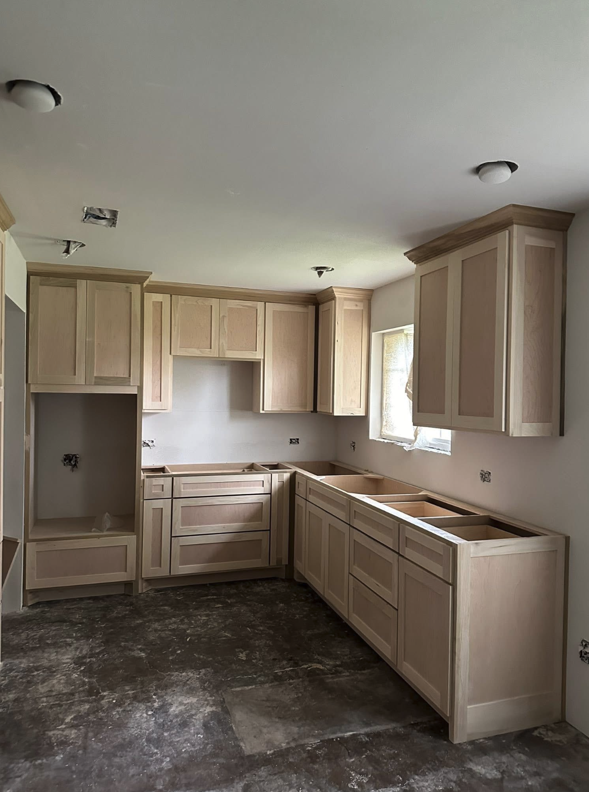 Kitchen cabinets installed, partially finished with open spaces for appliances and countertops, during construction or renovation.