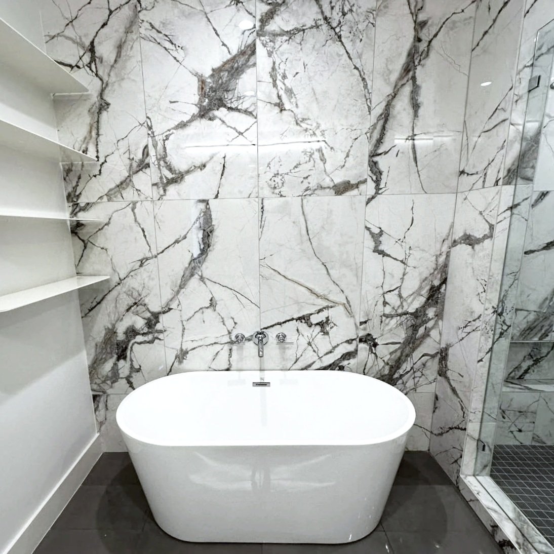 Modern bathroom with a white freestanding bathtub and marble wall tiles.