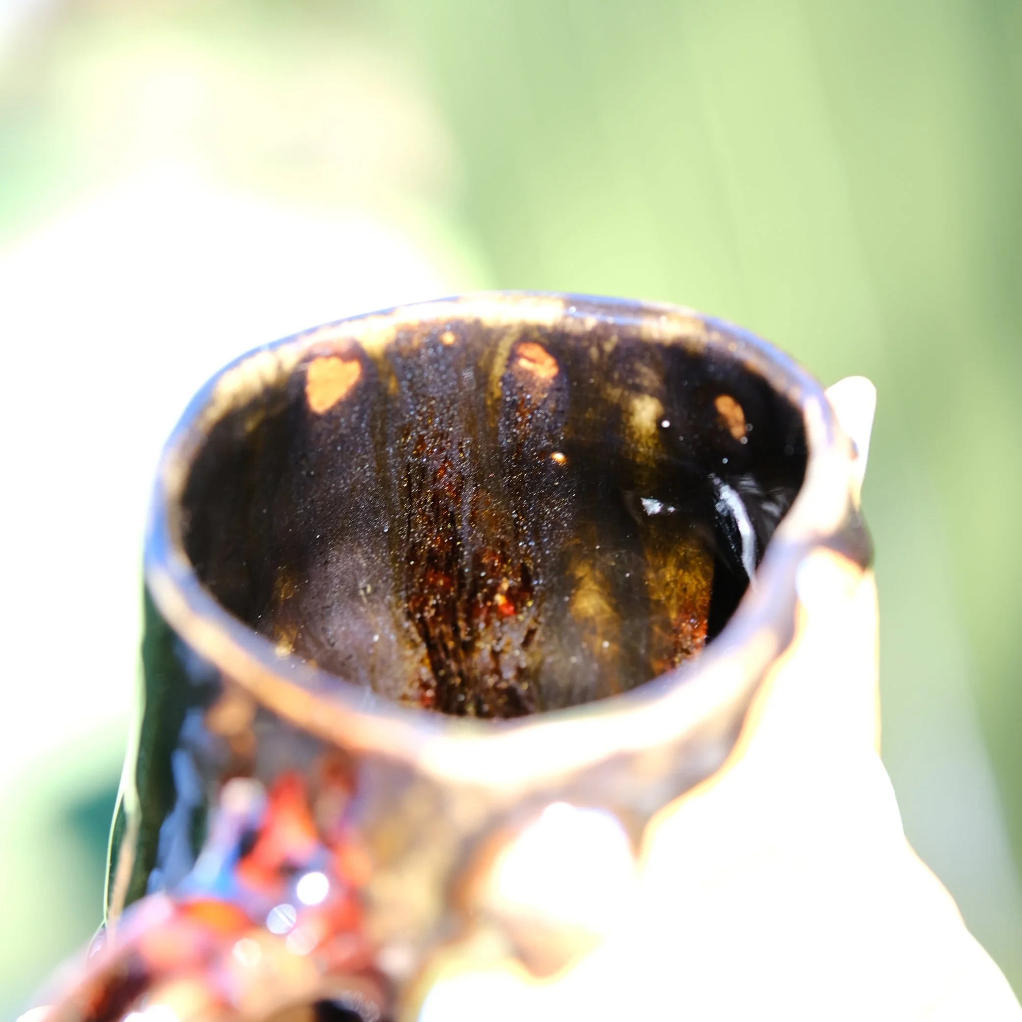 Detail shot of the sculptural horns and the unique amber treacle glaze dripping over the black stoneware of the Shadow Fairy mug.