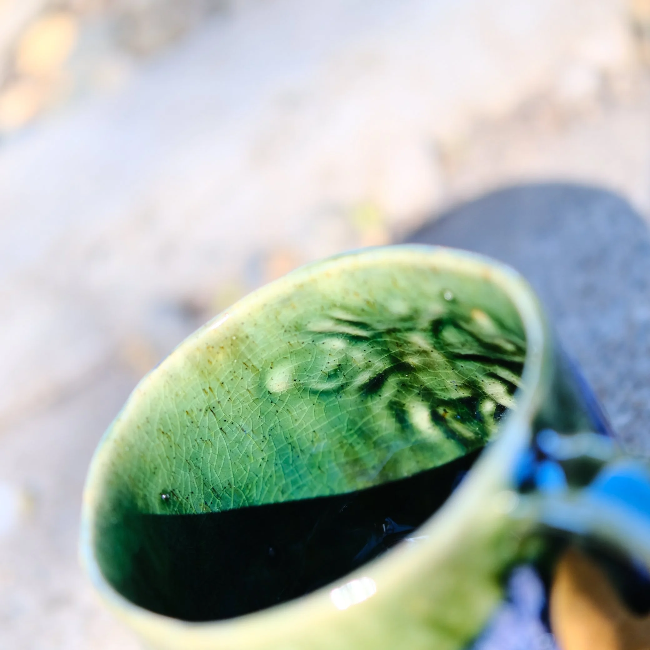 Looking down into the Sunshine Bee mug, showing the smooth internal glaze and the unique transition of green and purple exterior colors.