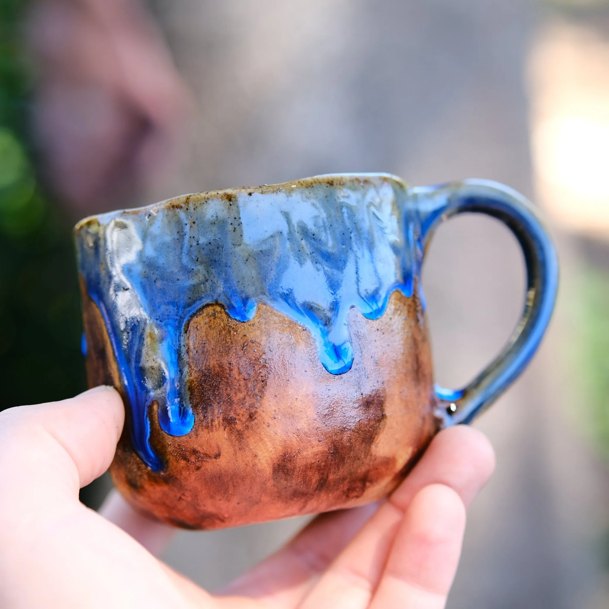 Macro shot of the ritualistic eye carving and dot patterns on a handcrafted stoneware mug.