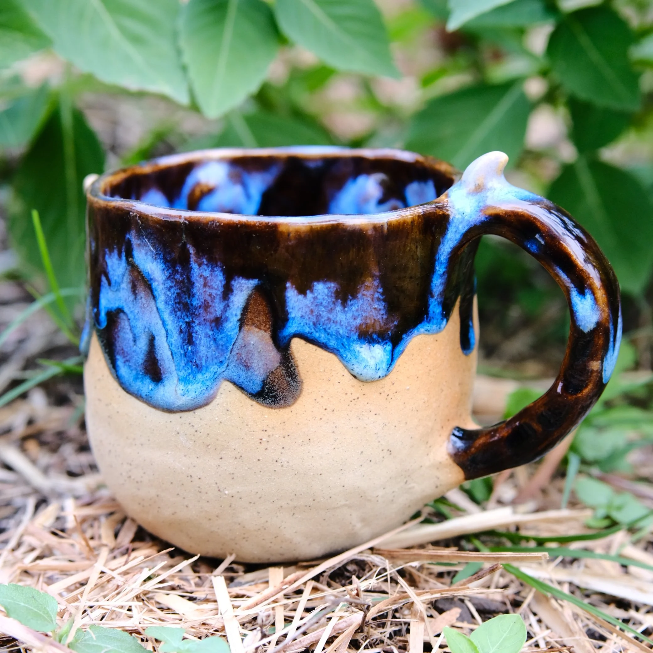 whimsical ceramic mug with sculpted face and horn handle fantasy style