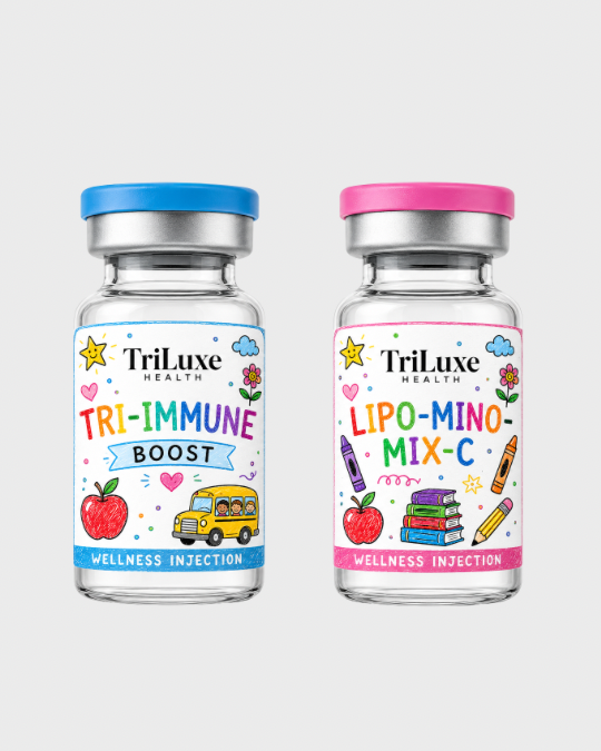 Two small bottles of health supplements from TriLuxe, one labeled 'Tri-Immunе Boost' with a red apple, school bus, and colorful doodles, and the other labeled 'Lipo-Mino-Mix-C' with a red apple, stacked books, and colored pencils, both with pink or blue caps.