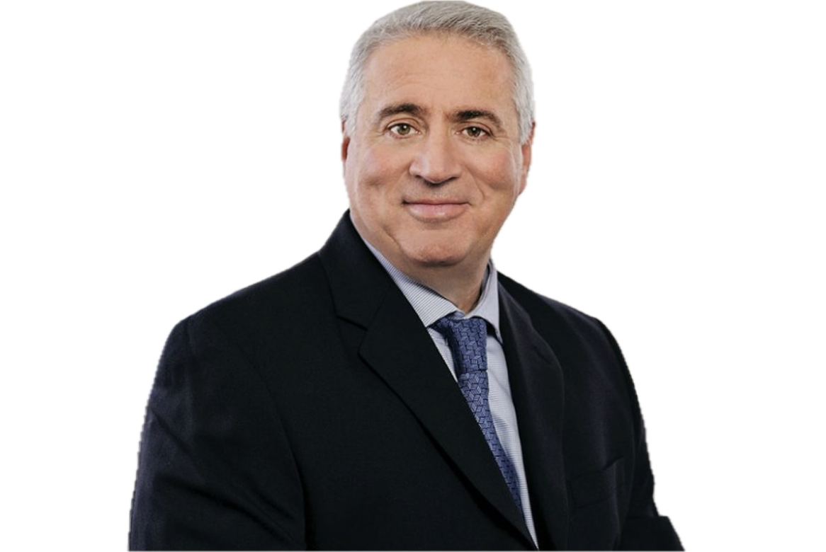A middle-aged man with gray hair, dressed in a dark suit, light blue shirt, and patterned blue tie, smiling at the camera.
