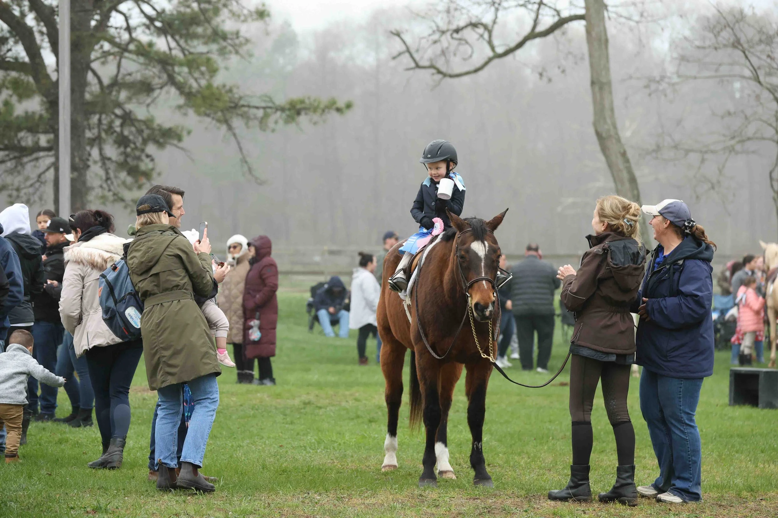 Young female equestrian jumping over an obstacle on a white horse at Hidden Pond Stables, Manorville, NY.