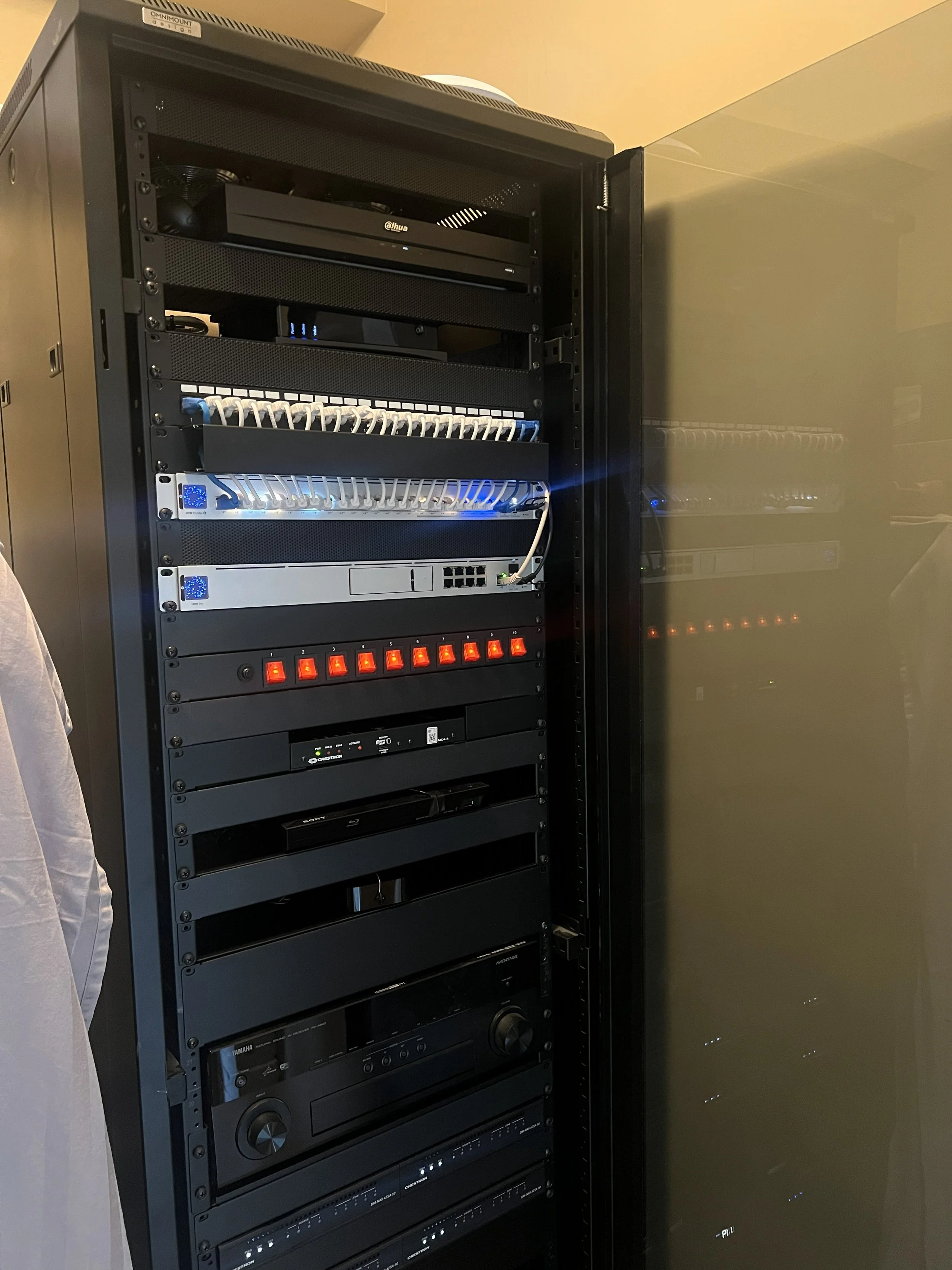 Server rack containing networking equipment, switches, and audio-visual components.
