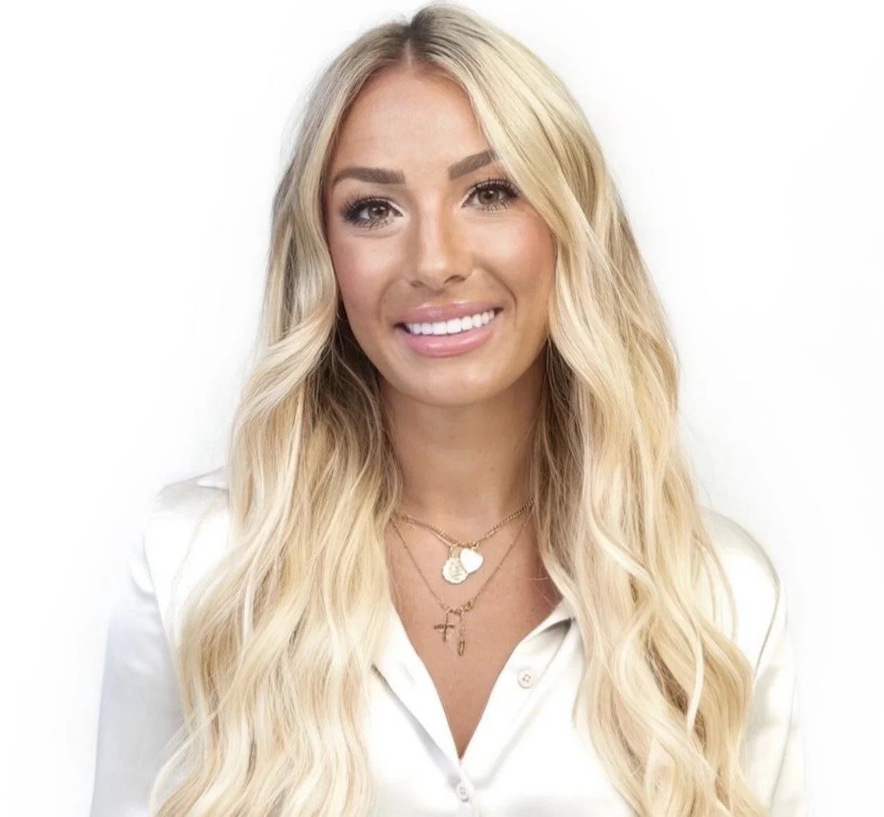 Portrait of a smiling woman with blonde hair in a black polka dot top against a white background.