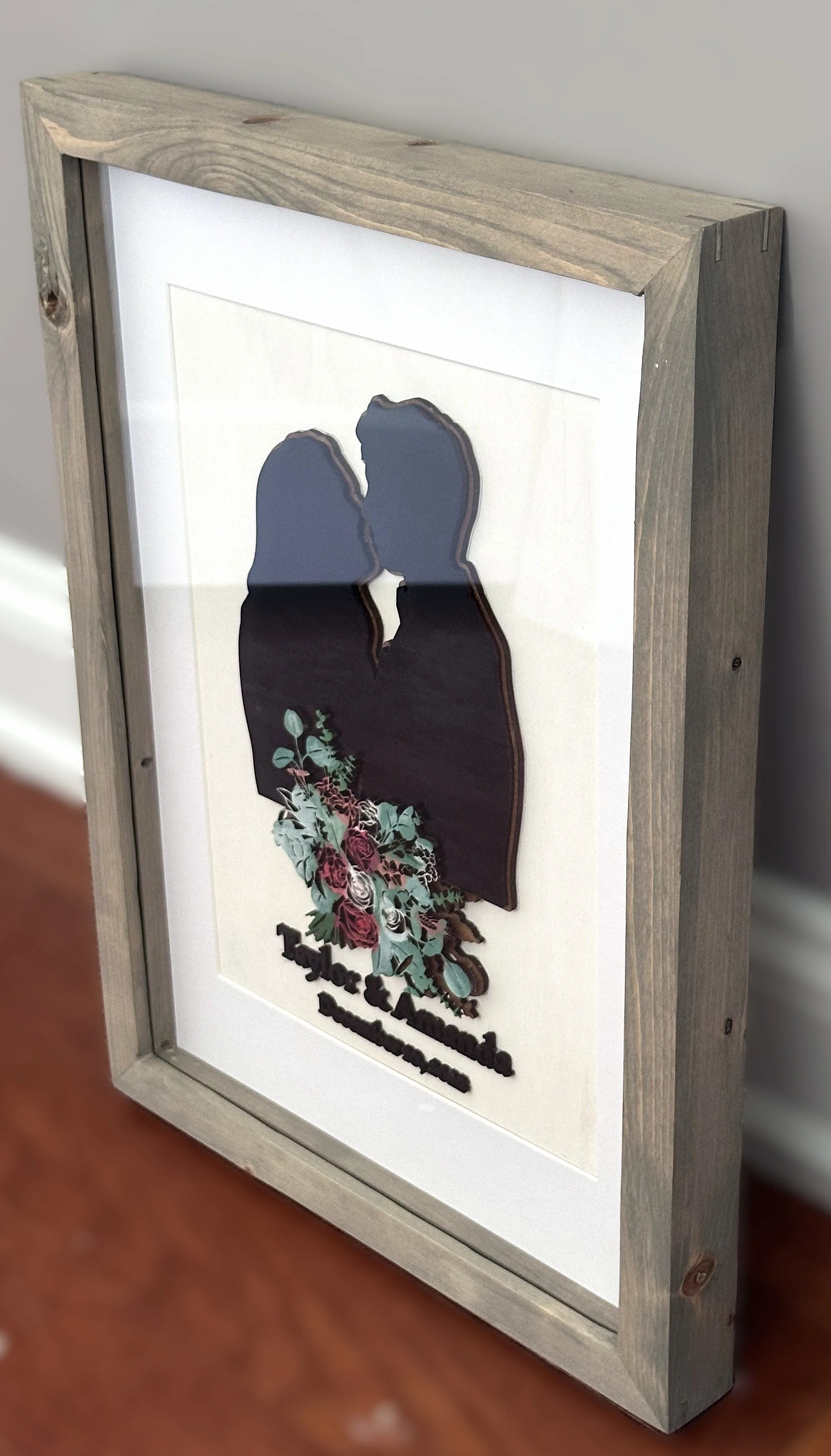 Framed art print featuring silhouette of a couple with a bouquet of flowers, with text 'Taylor & Amanda' and 'August 12, 2023'.