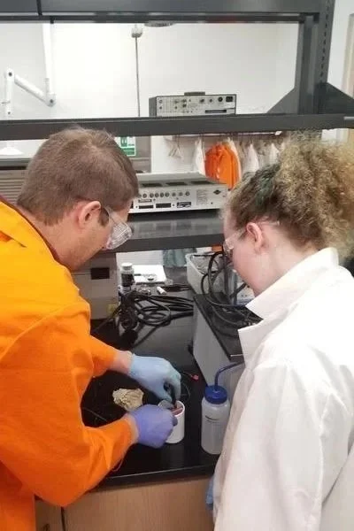 Two scientists in a laboratory working together at a bench with laboratory equipment and glassware.
