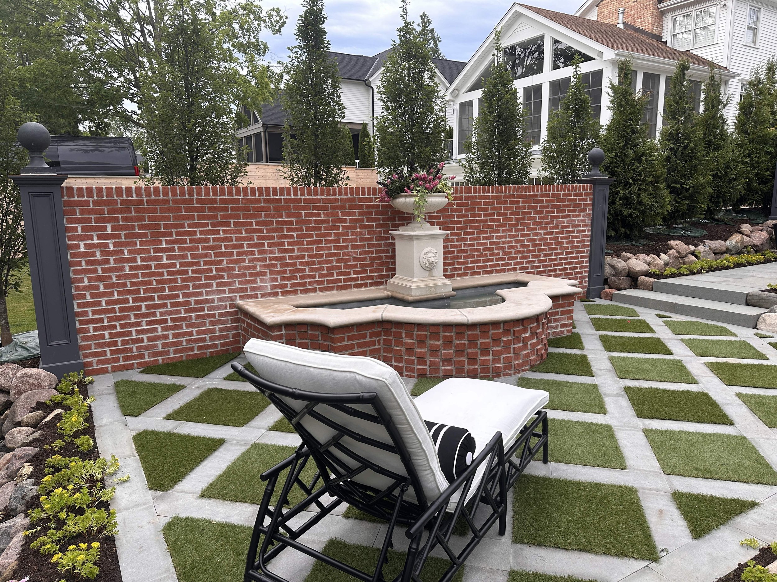 Brick retaining wall with water feature, paver patio with artificial turf