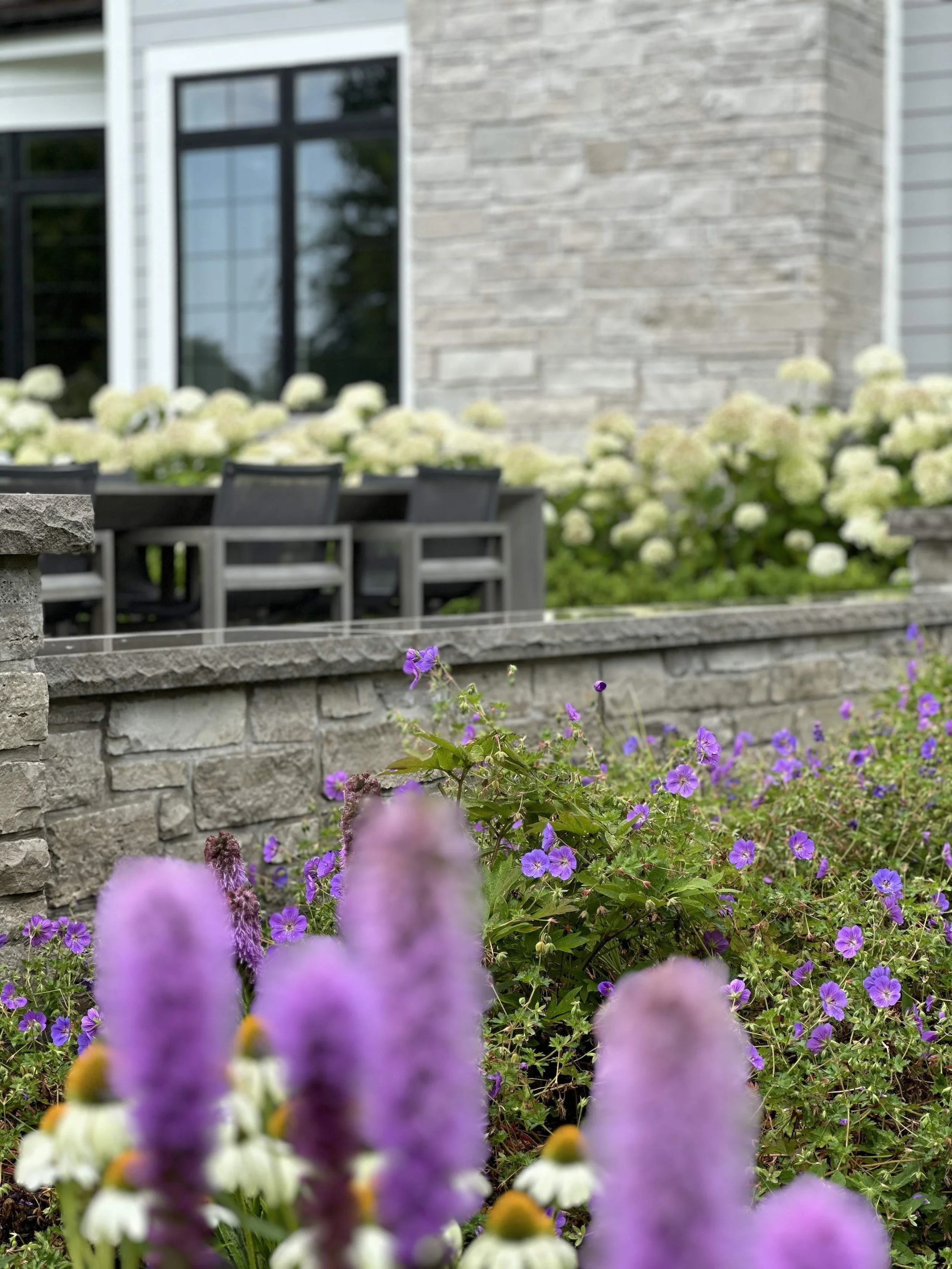 Stone retaining wall with flower beds and purple flowers